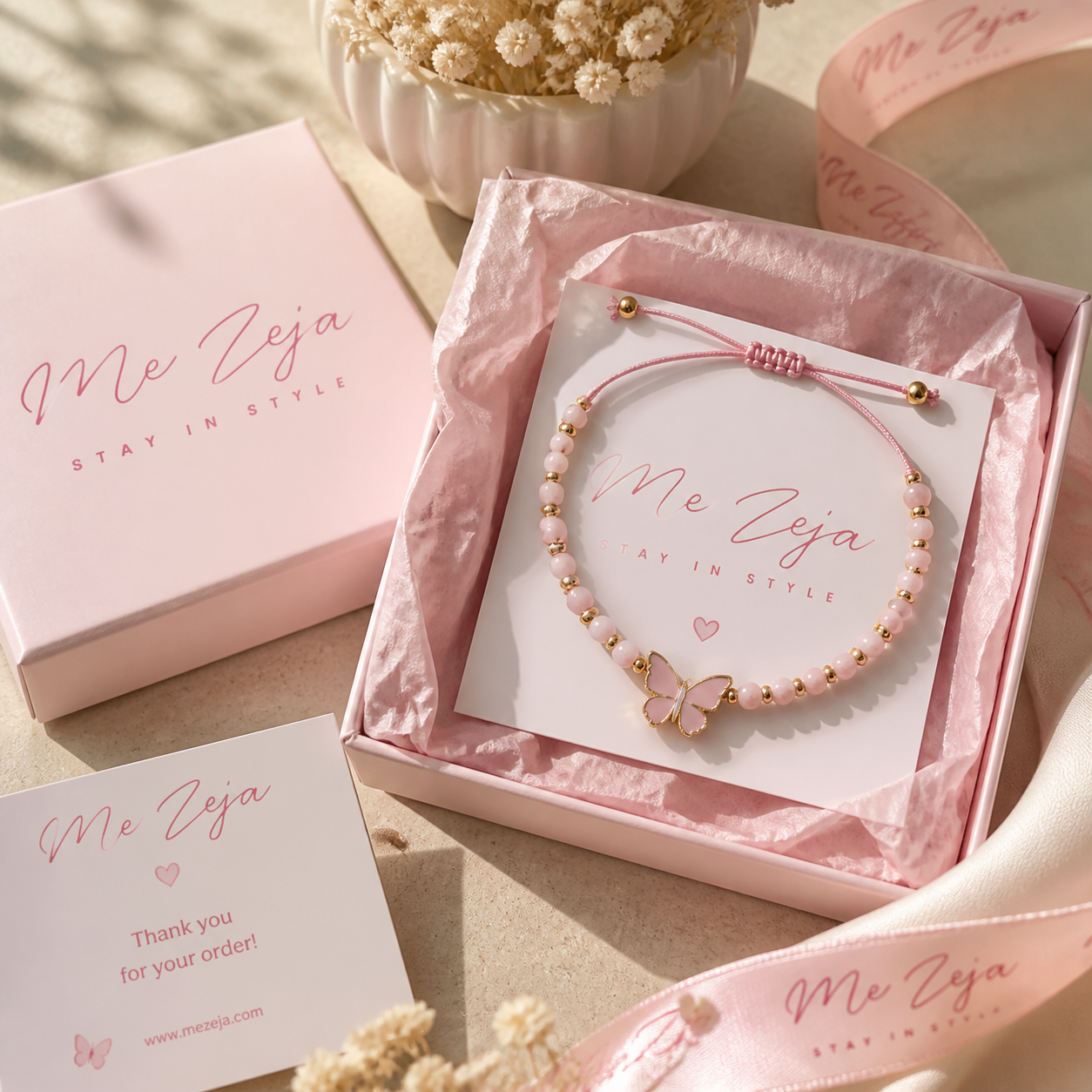 Pink gift boxes and a beaded bracelet on rose-hued packaging with “Me Ziya” branding.