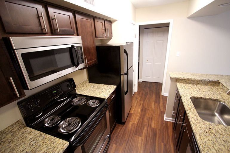 A kitchen with a stove , microwave , refrigerator and sink