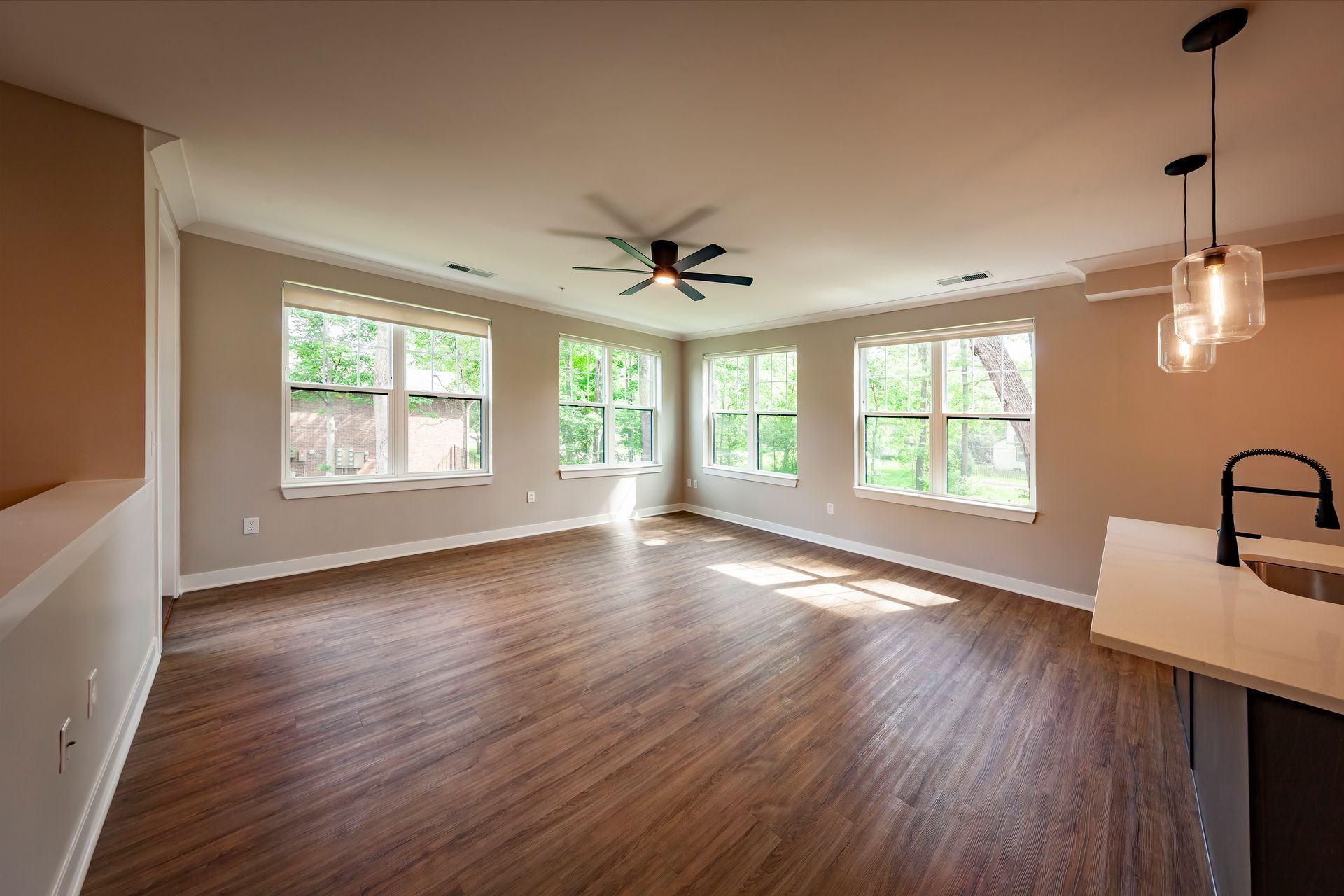 An empty living room with hardwood floors and a ceiling fan.
