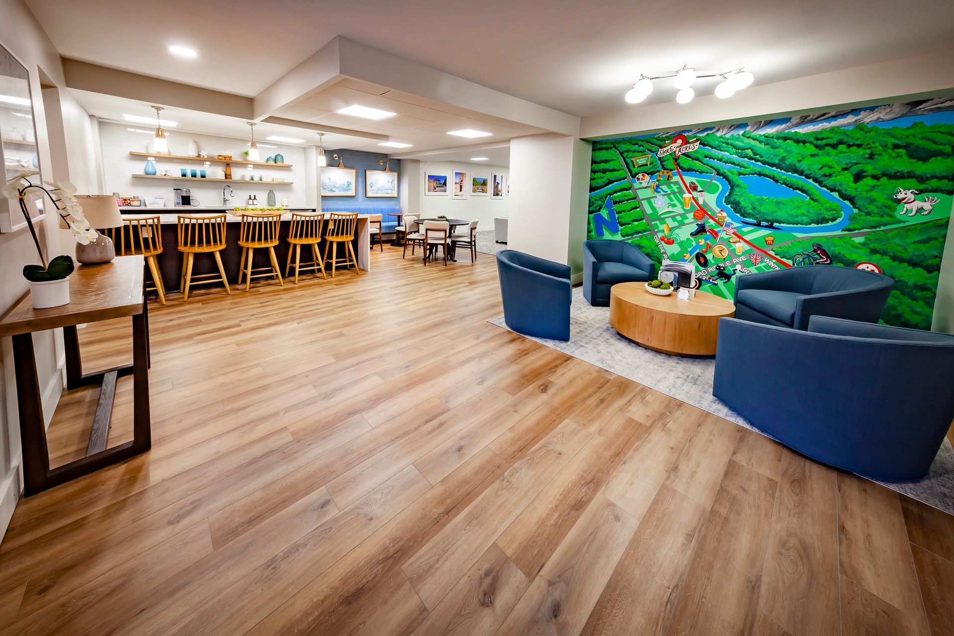 Clubhouse with wooden floors , chairs , tables and a mural on the wall.