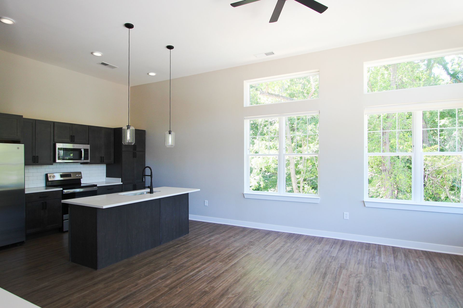 An empty kitchen with a large island and a ceiling fan.