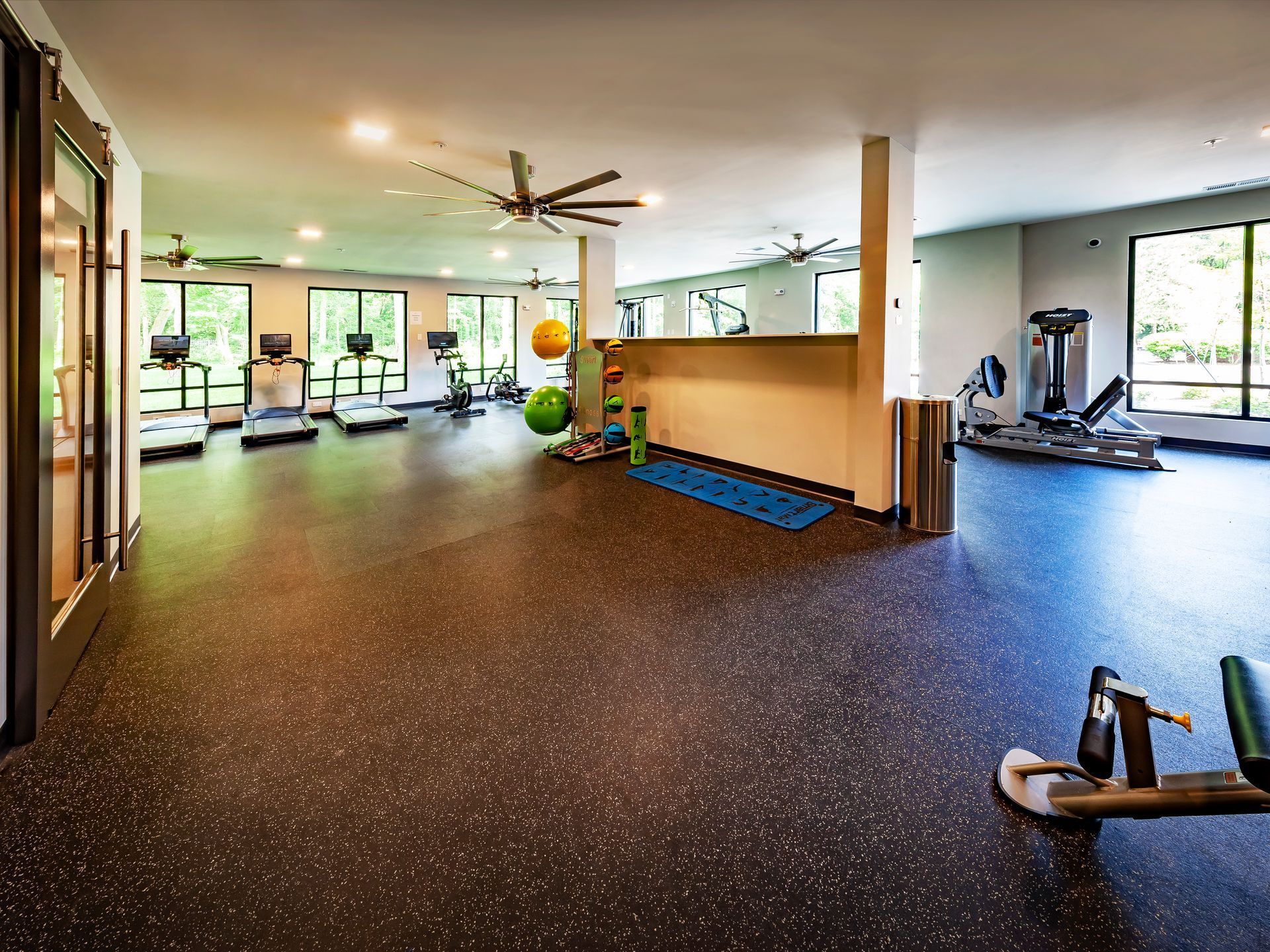 A clubhouse with wooden floors , chairs , tables and a mural on the wall.
