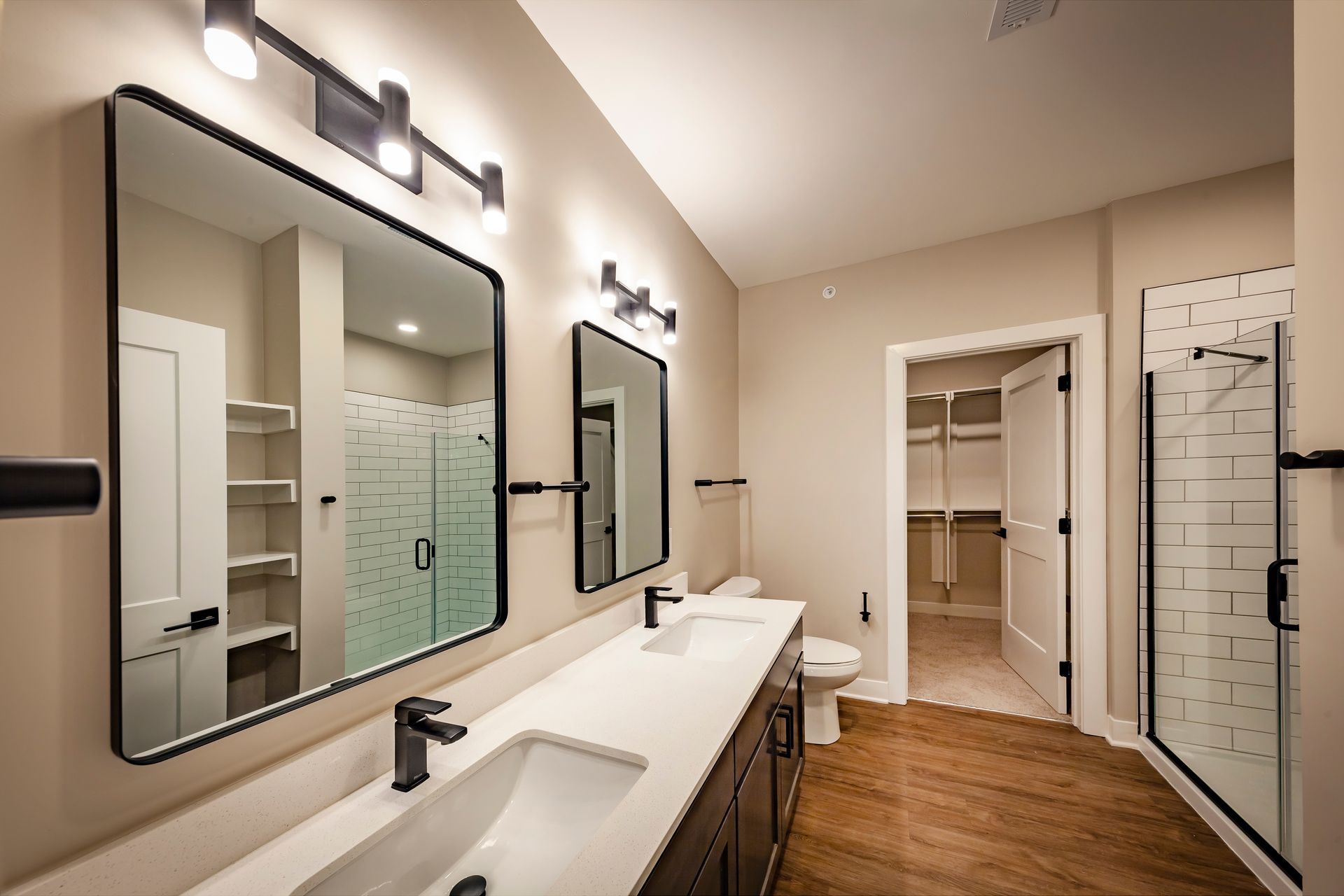 A bathroom with two sinks , a toilet , and a walk in closet.