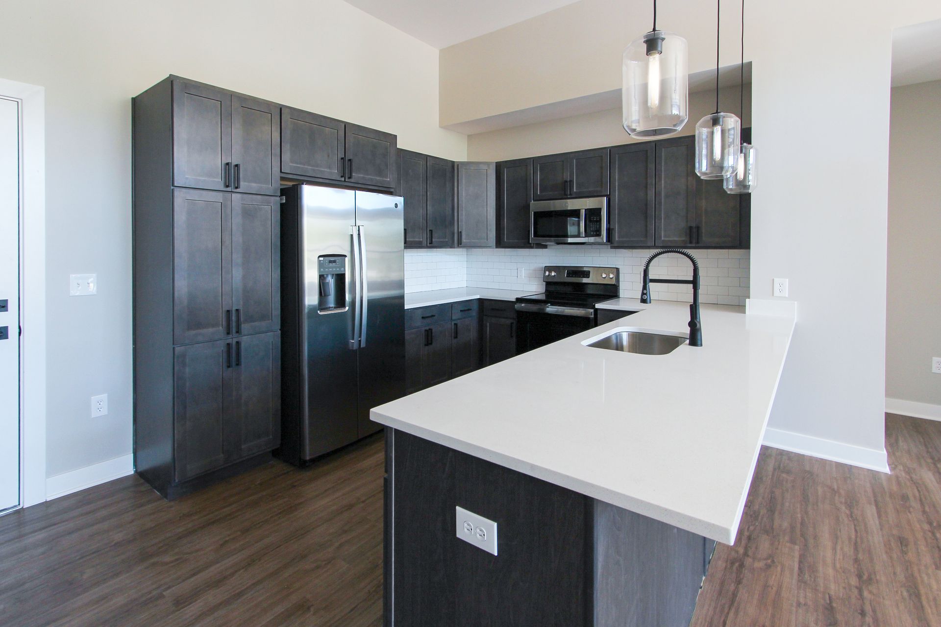 A kitchen with a stainless steel refrigerator , stove , sink , and cabinets.