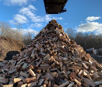 A large pile of wood is being lifted by a crane.