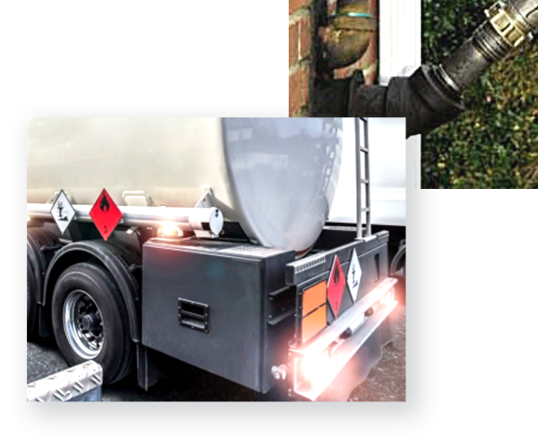 Fuel tanker with warning labels parked near a building with a connected hose, suggesting a fuel delivery.