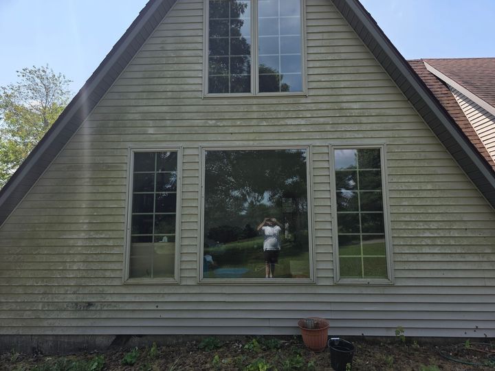 Front view of a green house with a large central window and steep roof.