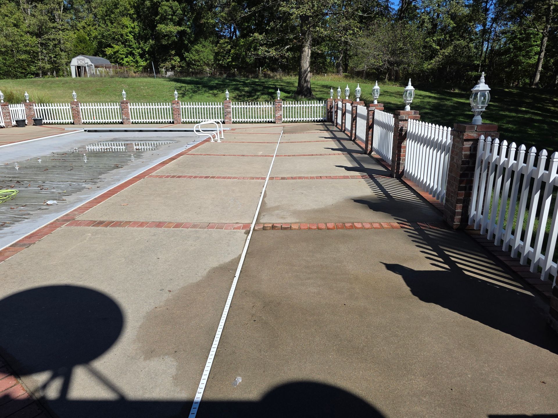 Concrete walkway with painted red lines and white railing beside a parking area on a sunny day