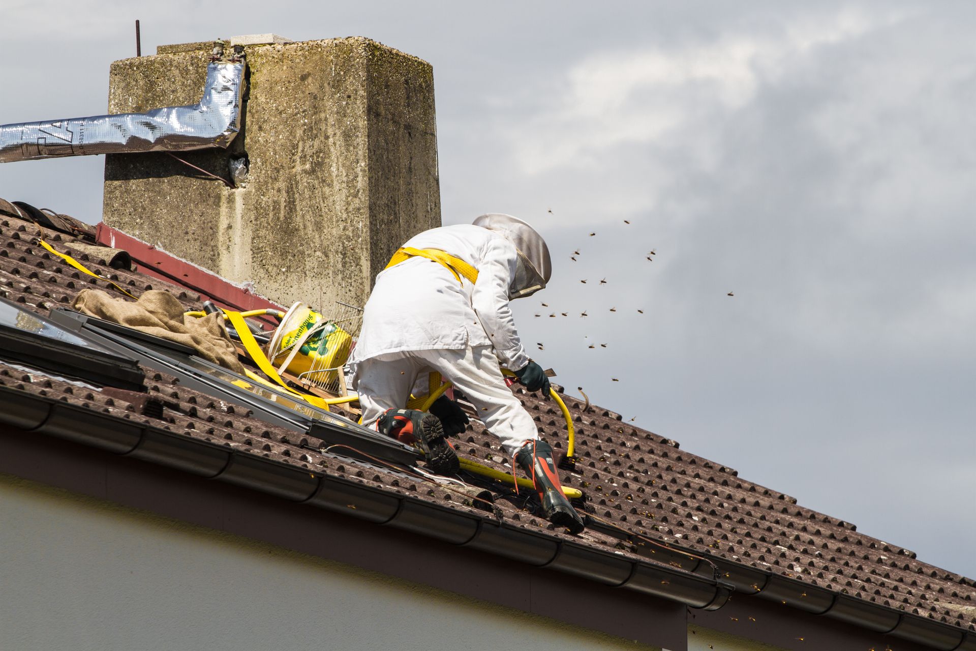 Person in protective suit working on a roof, near a chimney.