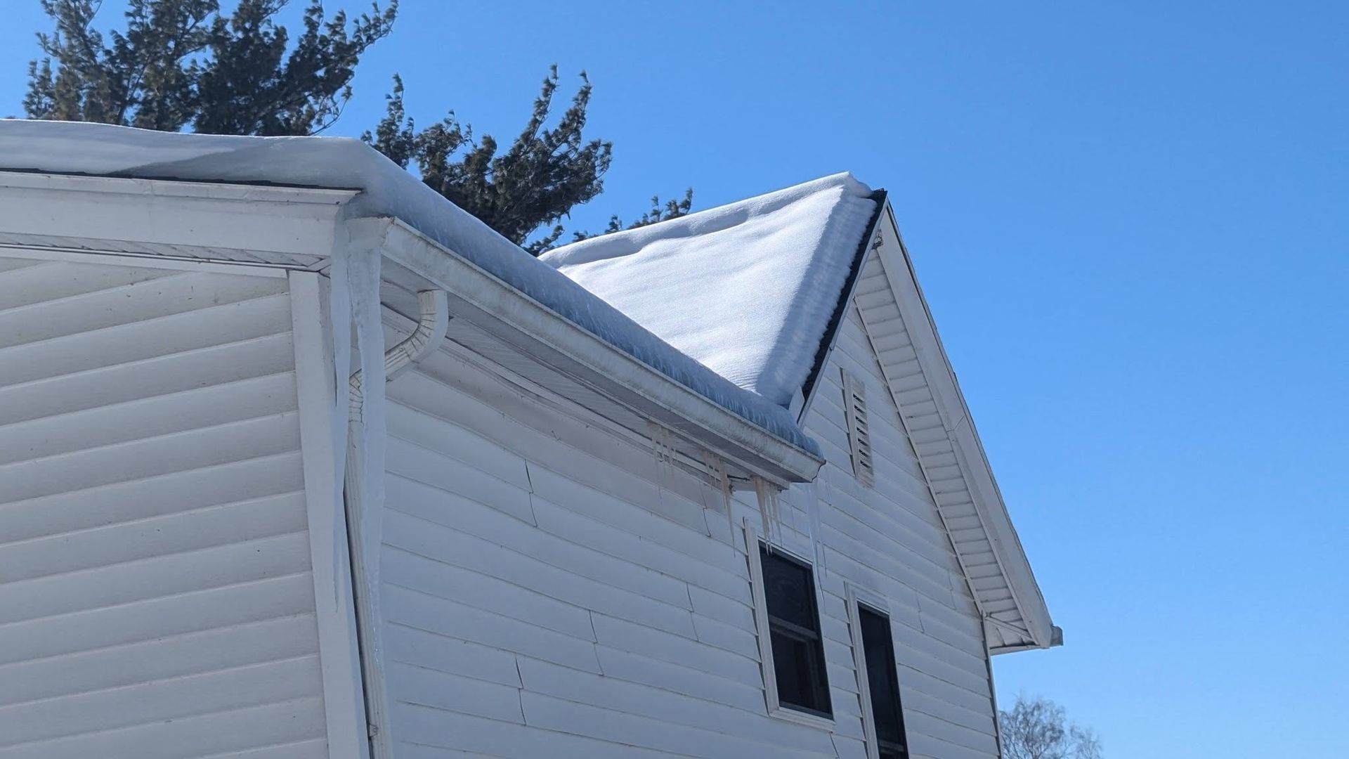 White house siding and steep roofline against a clear blue sky.