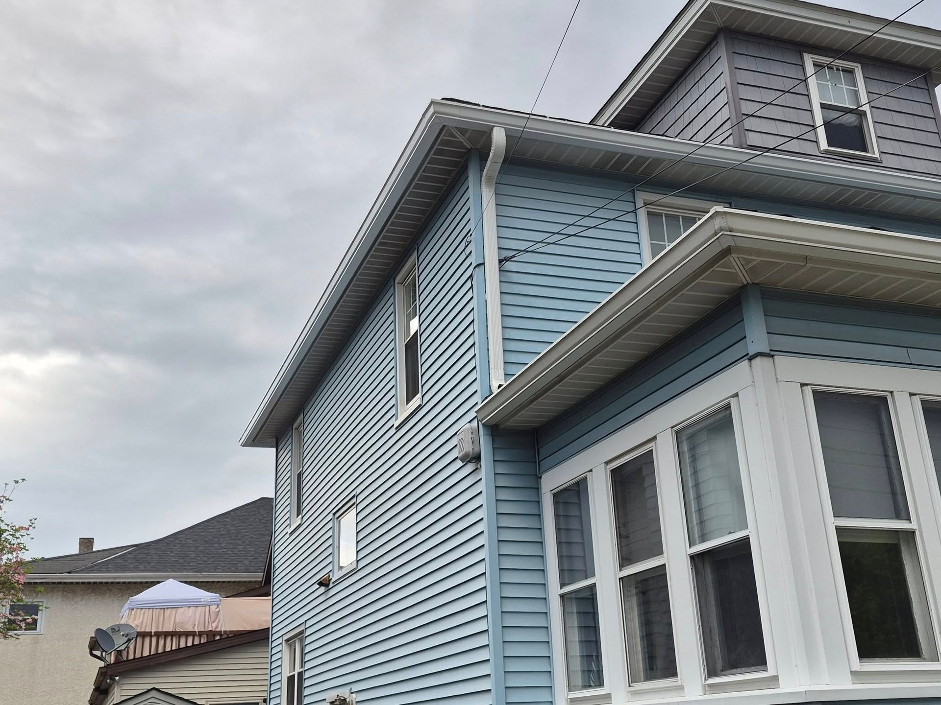 Light blue house exterior with white trim under a cloudy sky