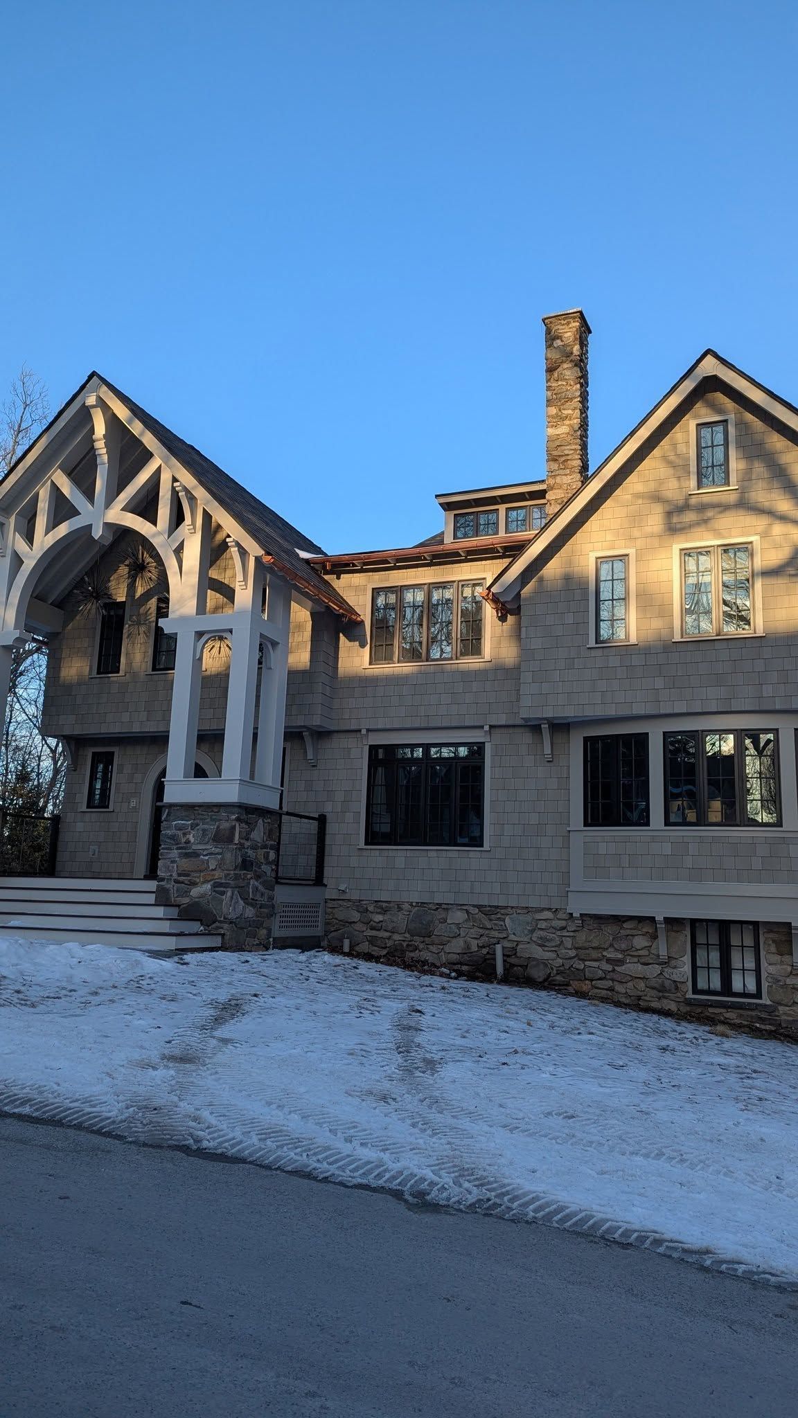 Snow-covered Tudor-style house with stone and timber facade on a clear winter day