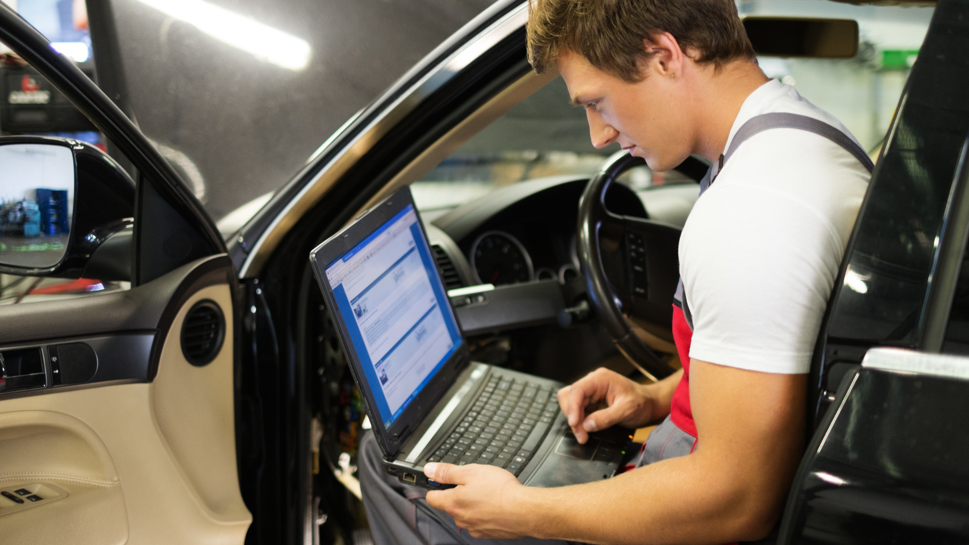 technician checking PCM tuning data on laptop connected to car