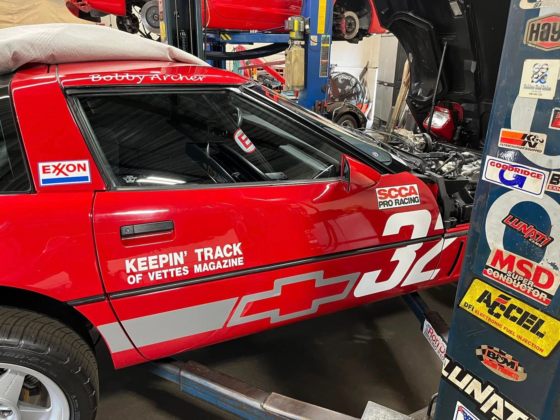 A red race car with the number 32 on the side is parked in a garage.