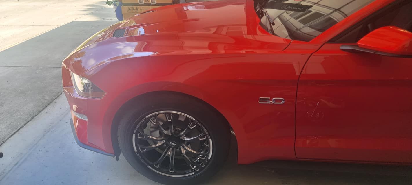 A red ford mustang is parked in a driveway.
