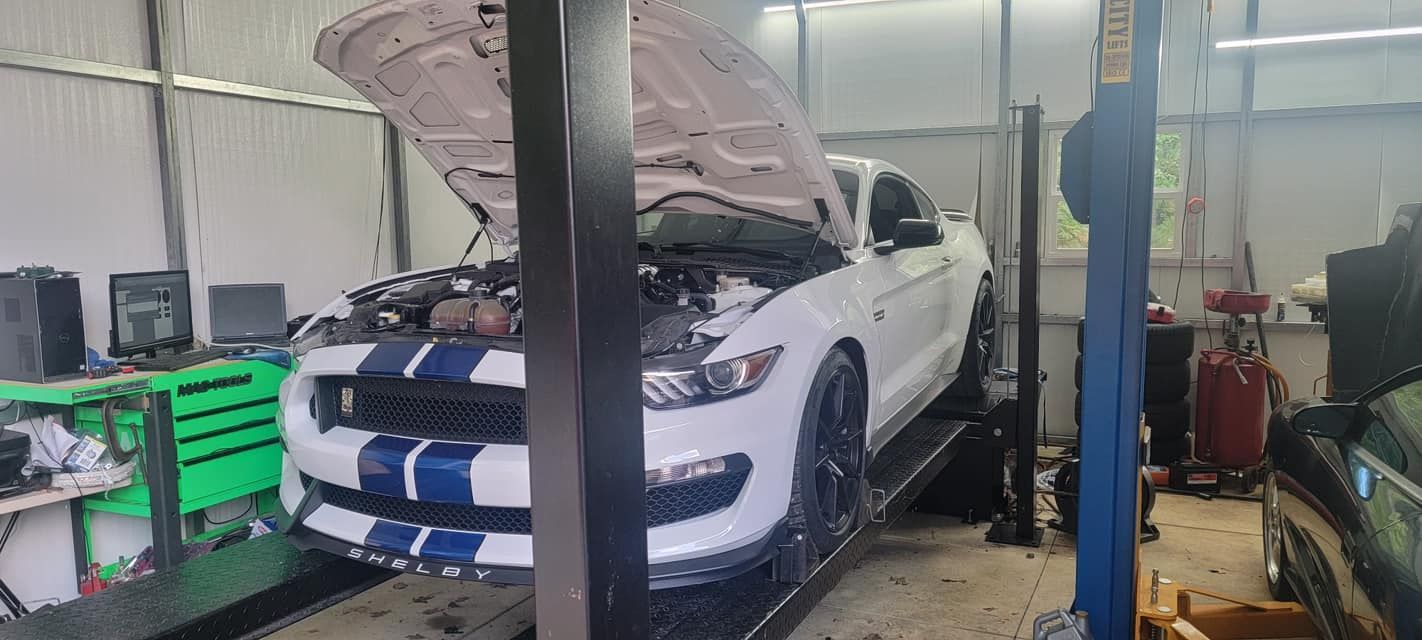 A white ford mustang is sitting on a lift in a garage.