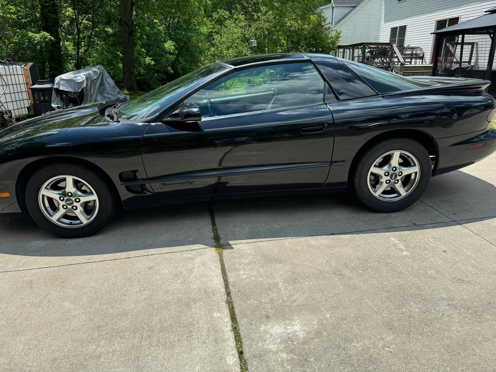A black car is parked in a driveway next to a house.