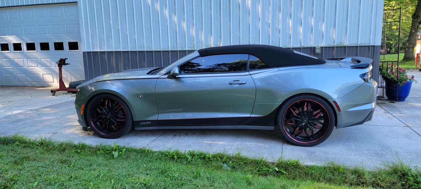 A silver convertible car is parked in front of a garage.