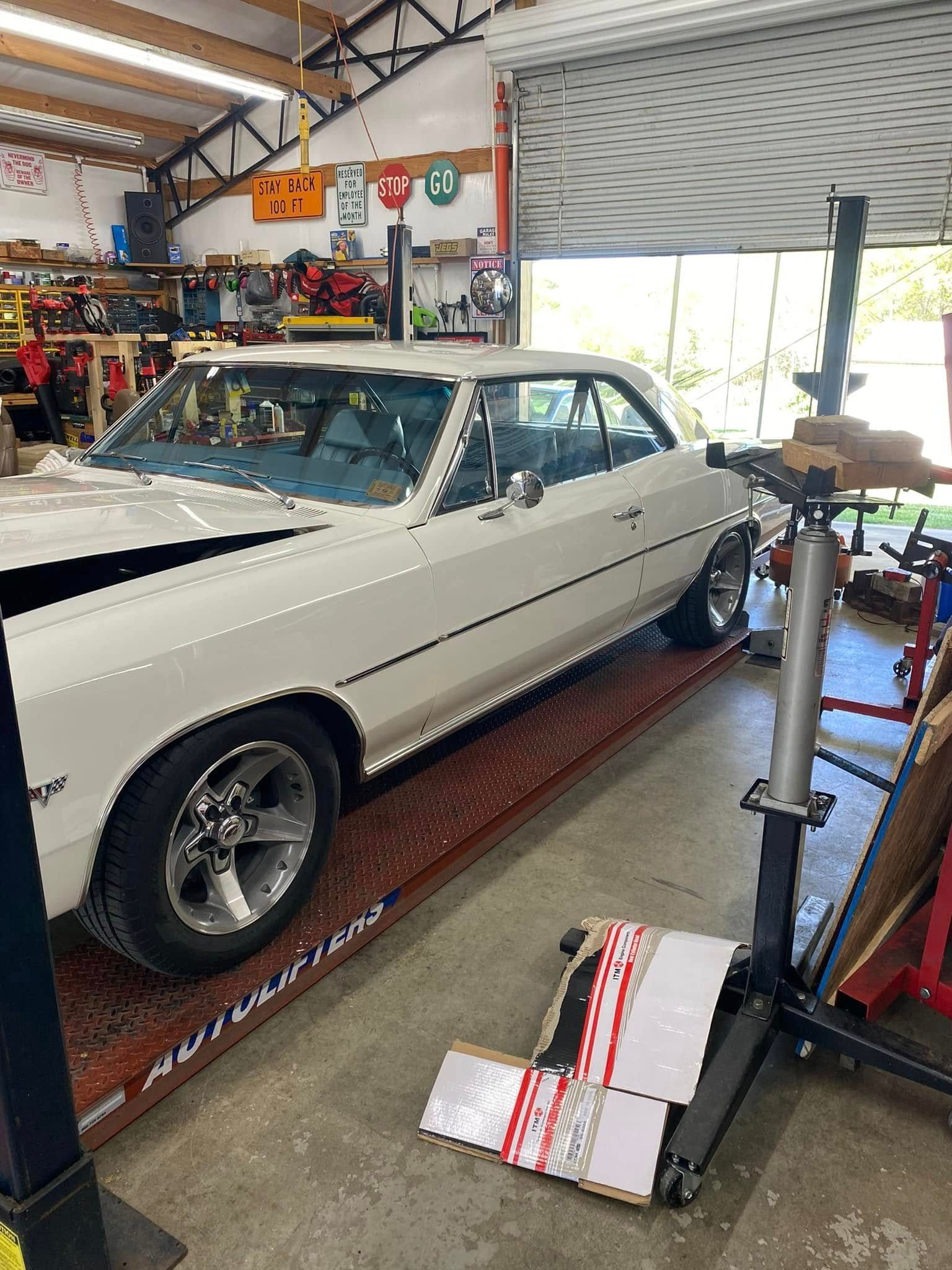 A white car is parked on a lift in a garage.