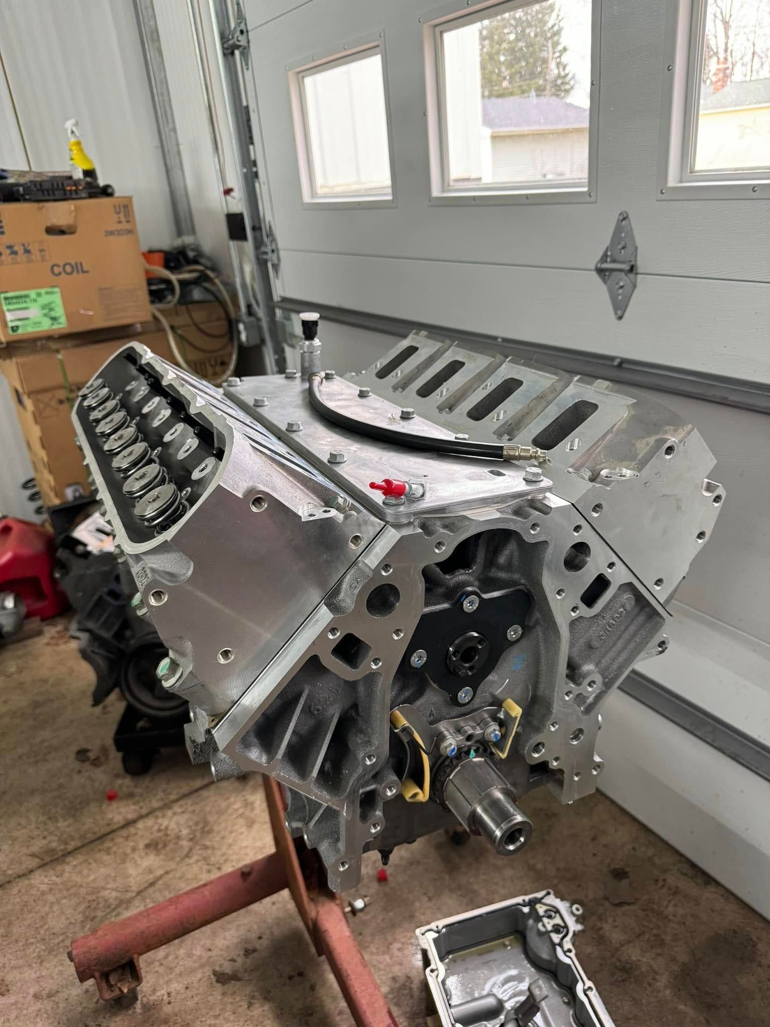 A car engine is sitting on a stand in a garage.