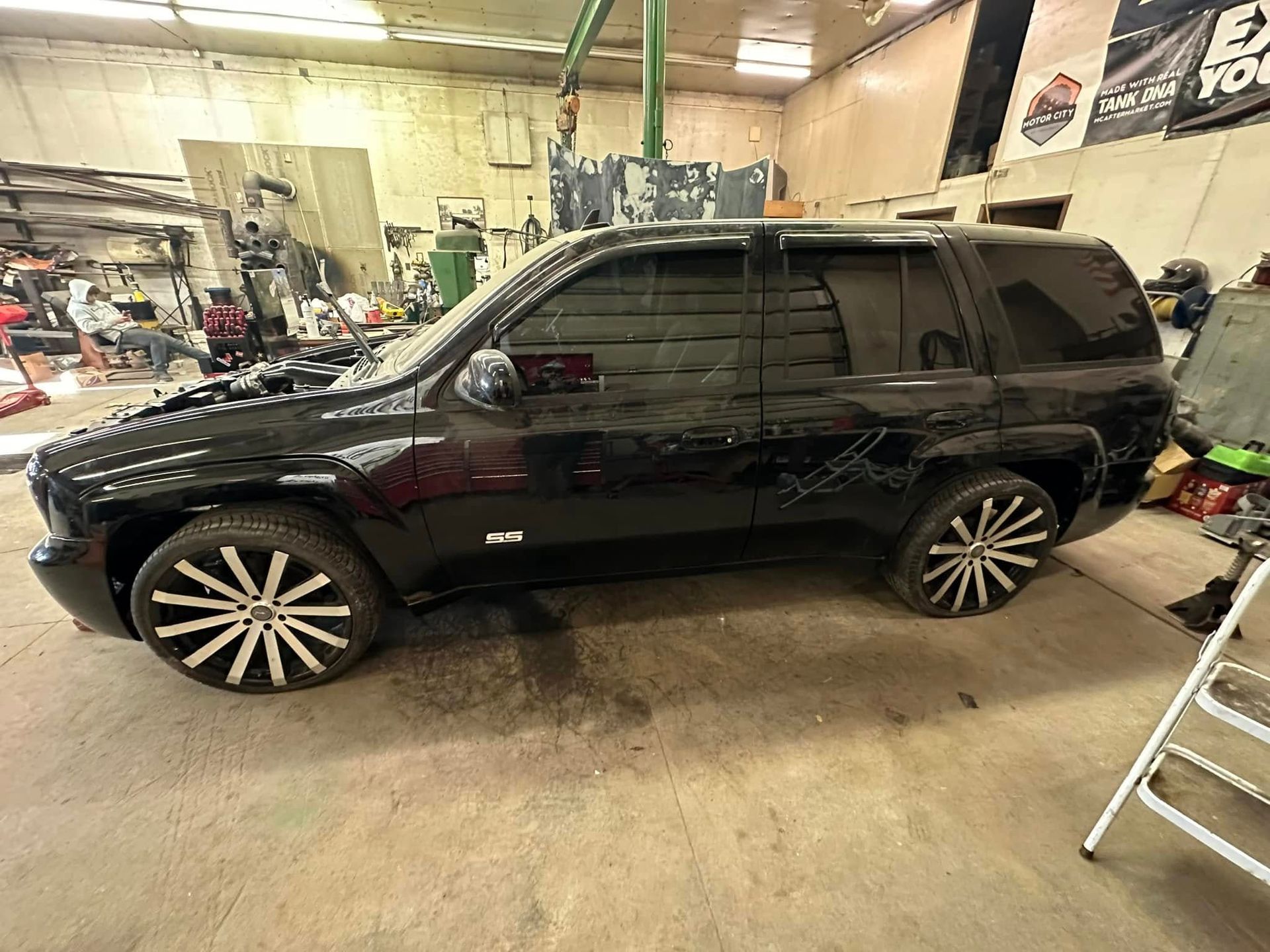 A black suv is parked in a garage next to a ladder.