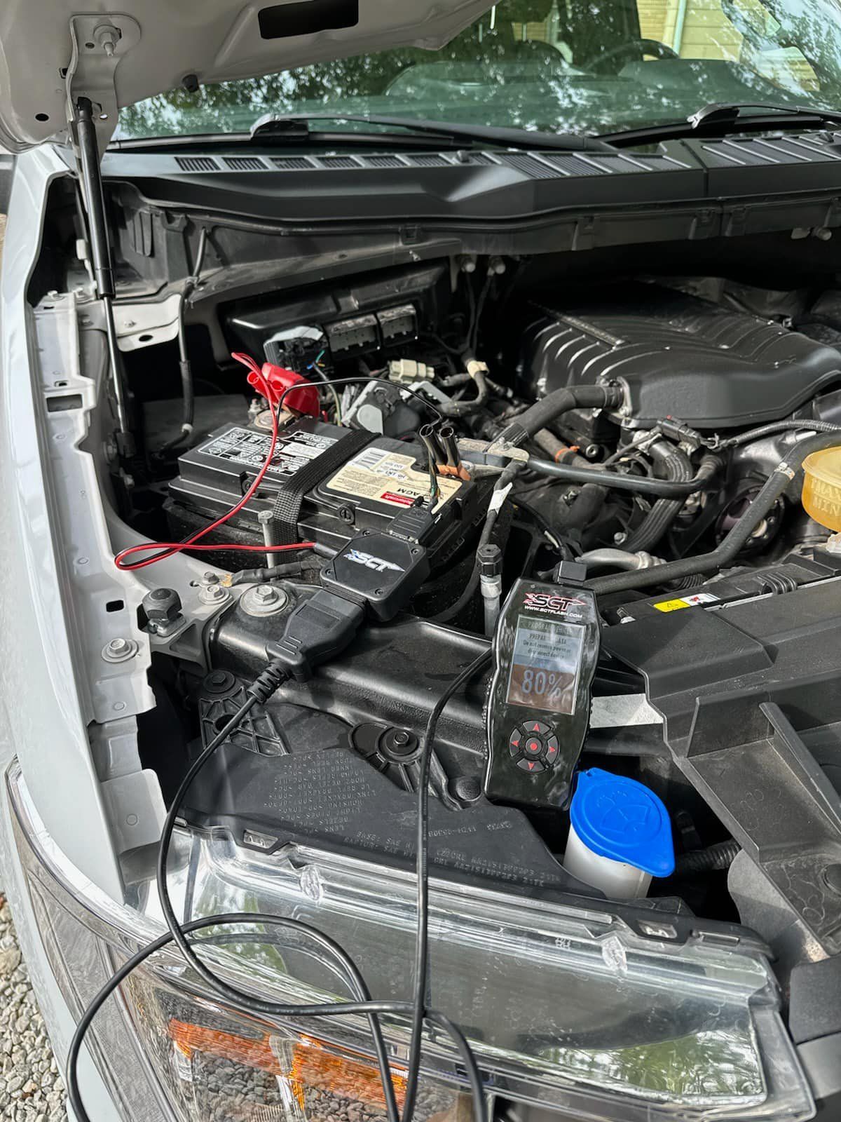 A close up of a car engine with the hood open.