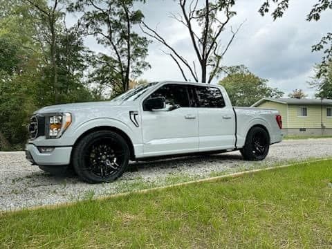A white pickup truck is parked on the side of a gravel road.