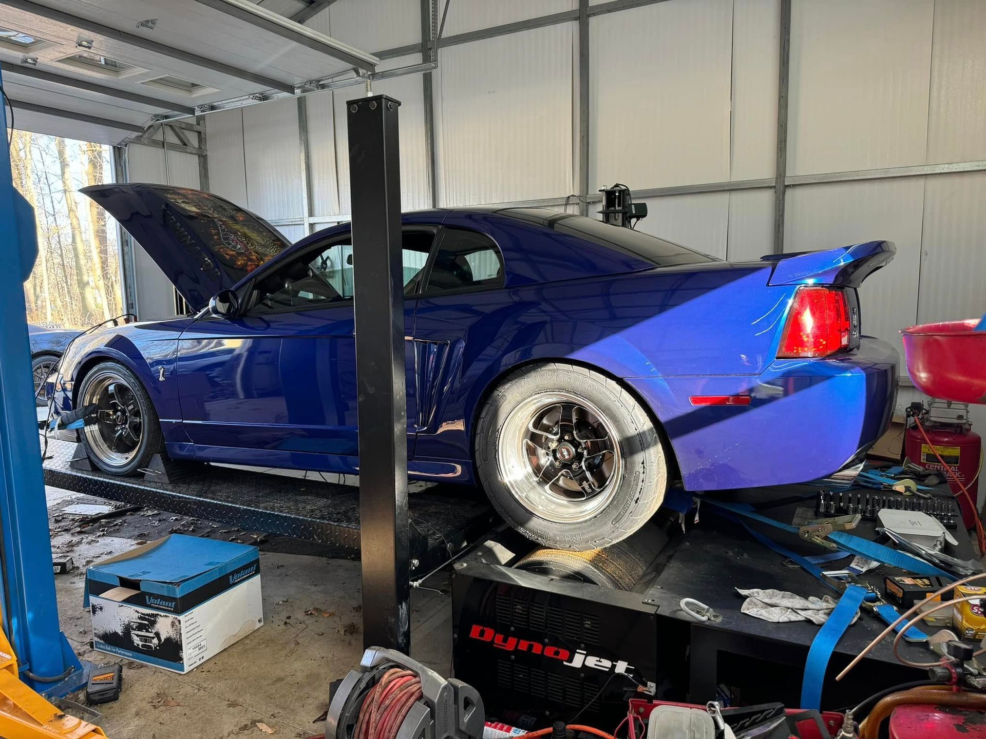 A blue car is sitting on a lift in a garage.
