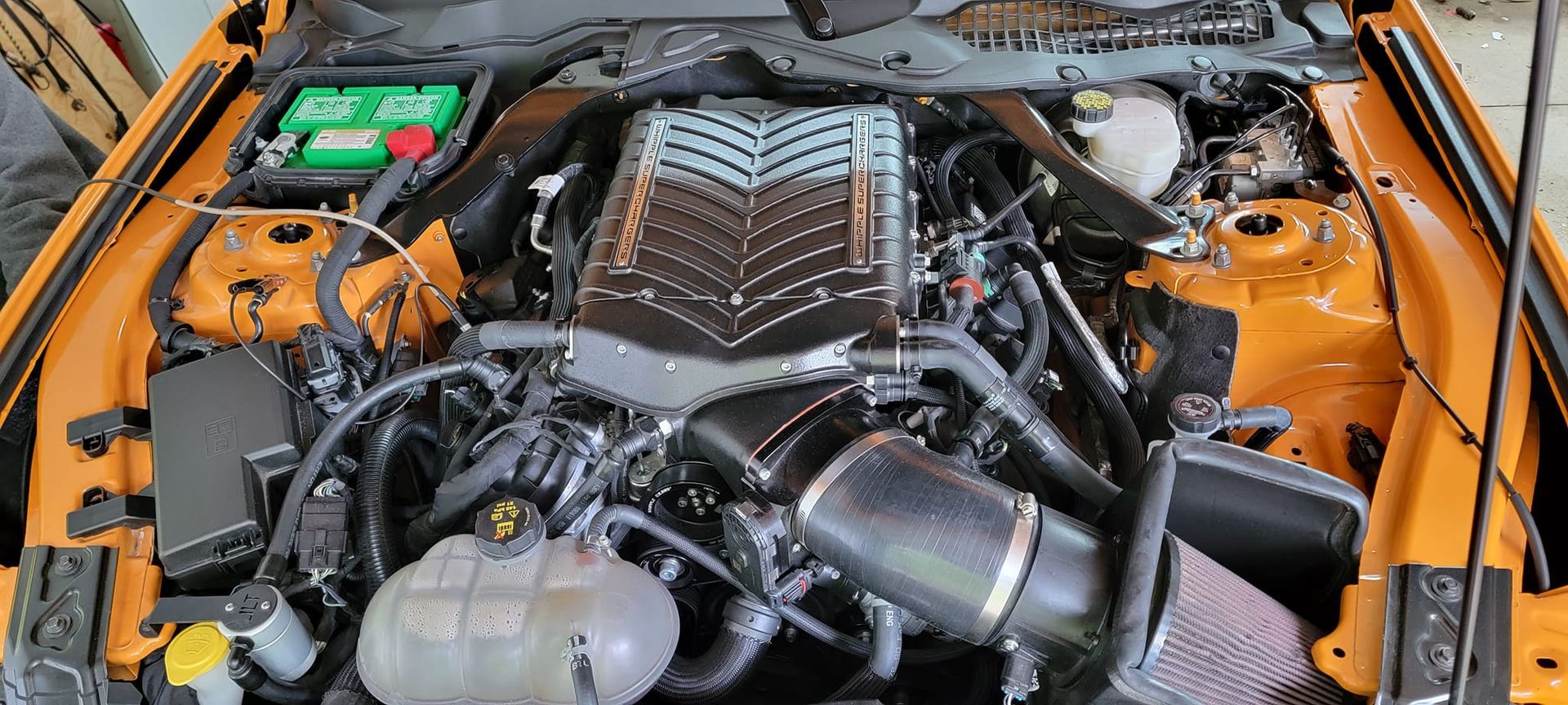 A close up of a car engine with the hood open.