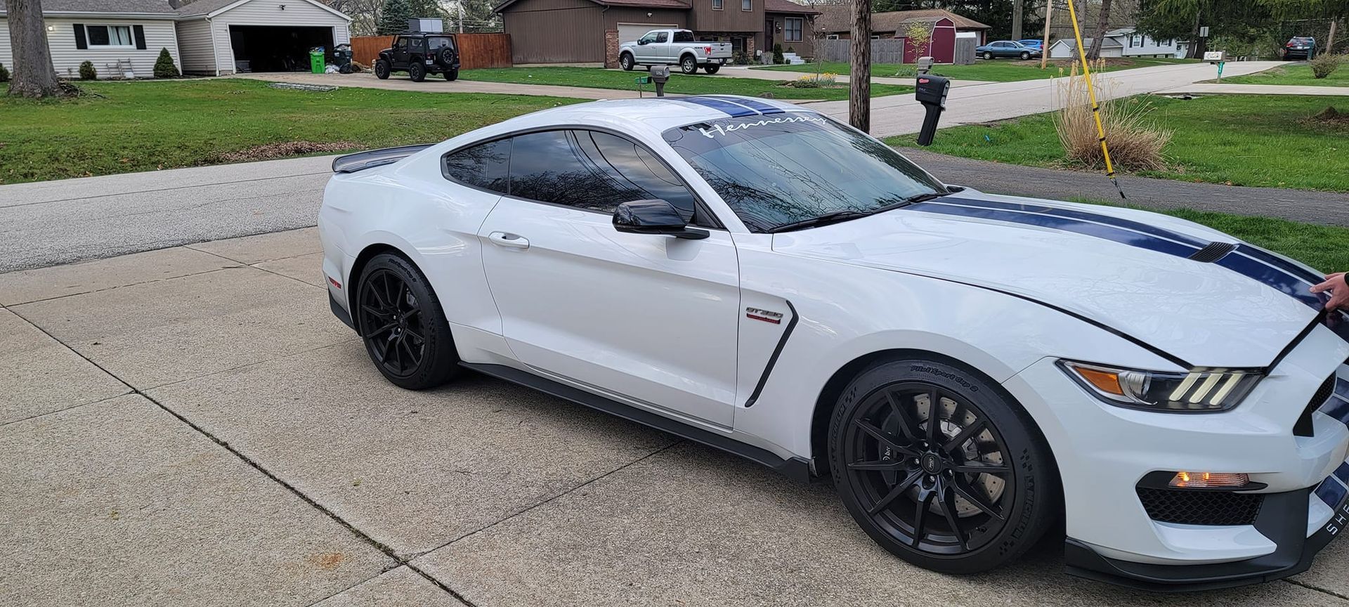 A white ford mustang is parked in a driveway.