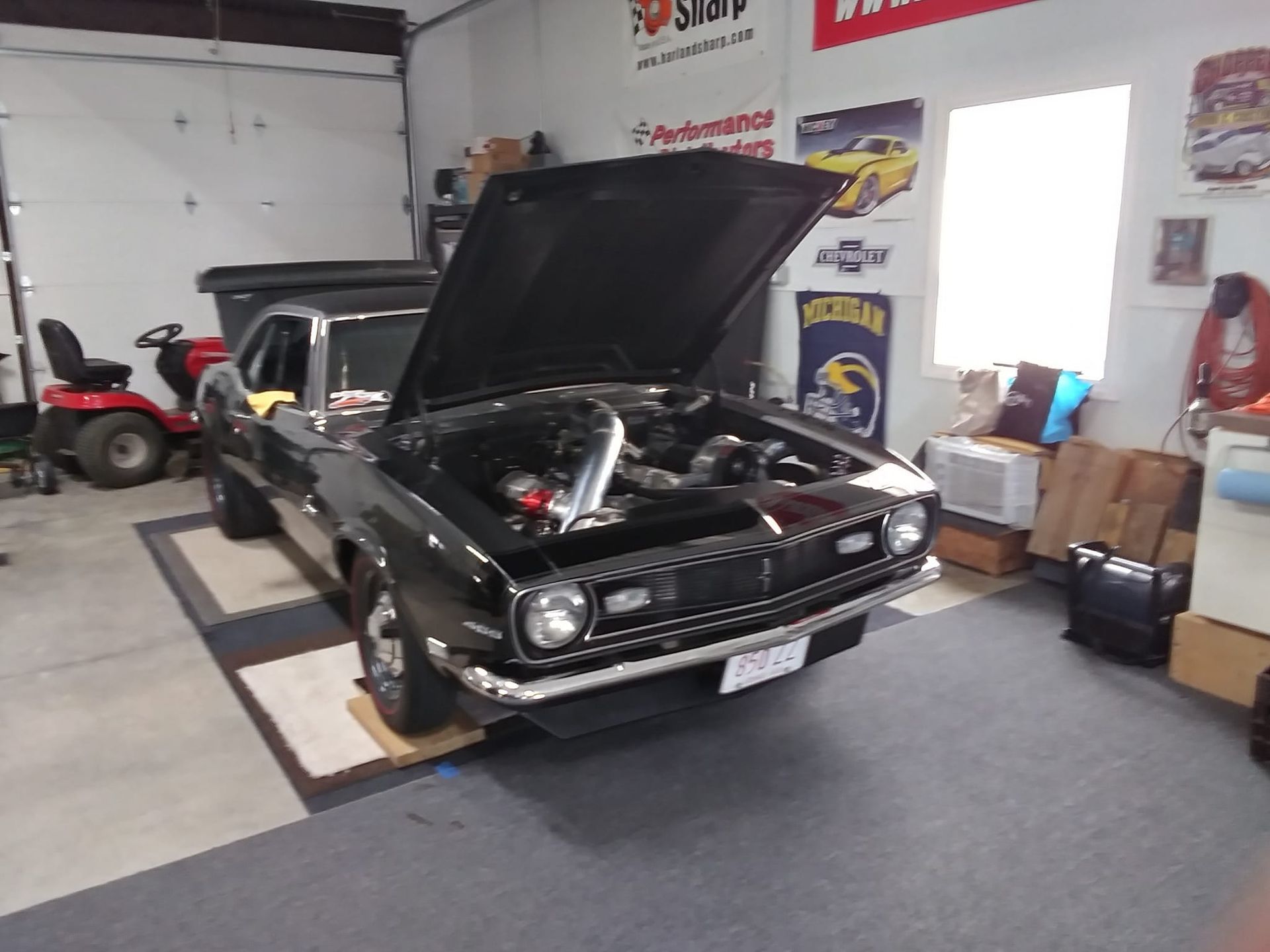 A black car with the hood up in a garage