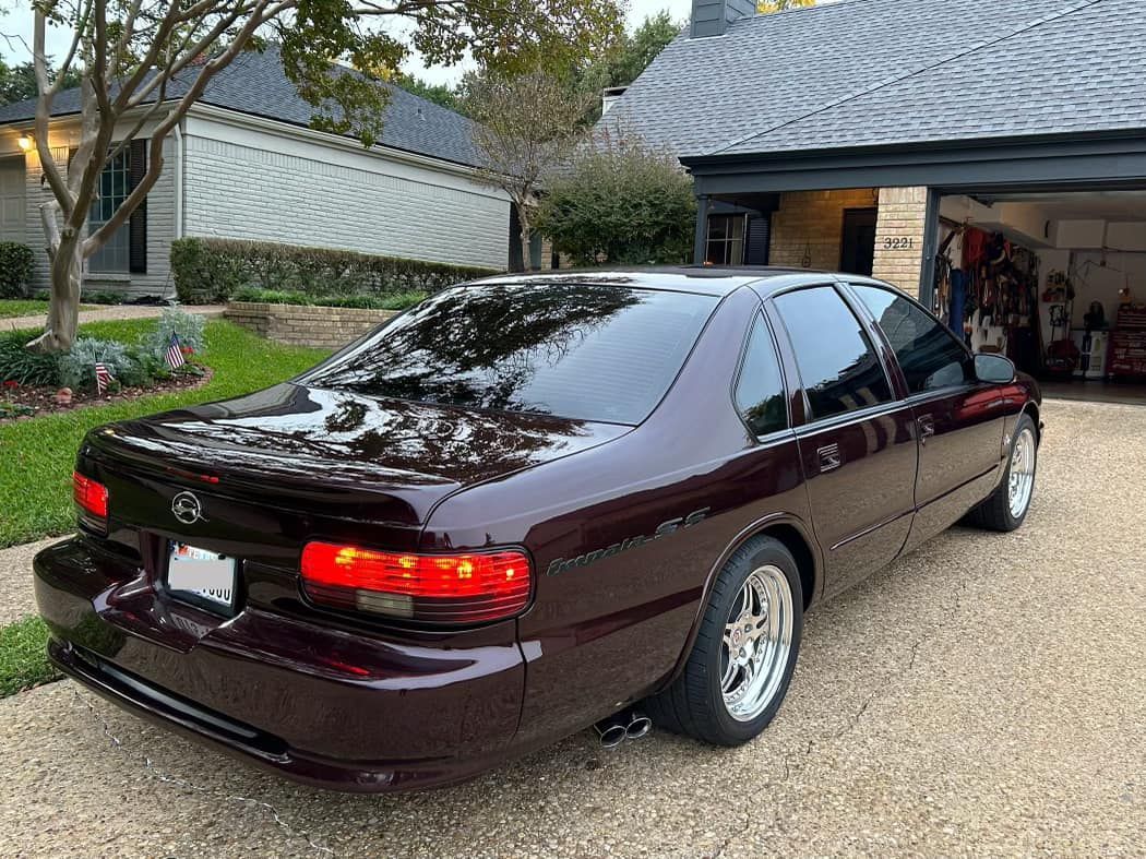 A burgundy car is parked in front of a house in a driveway.