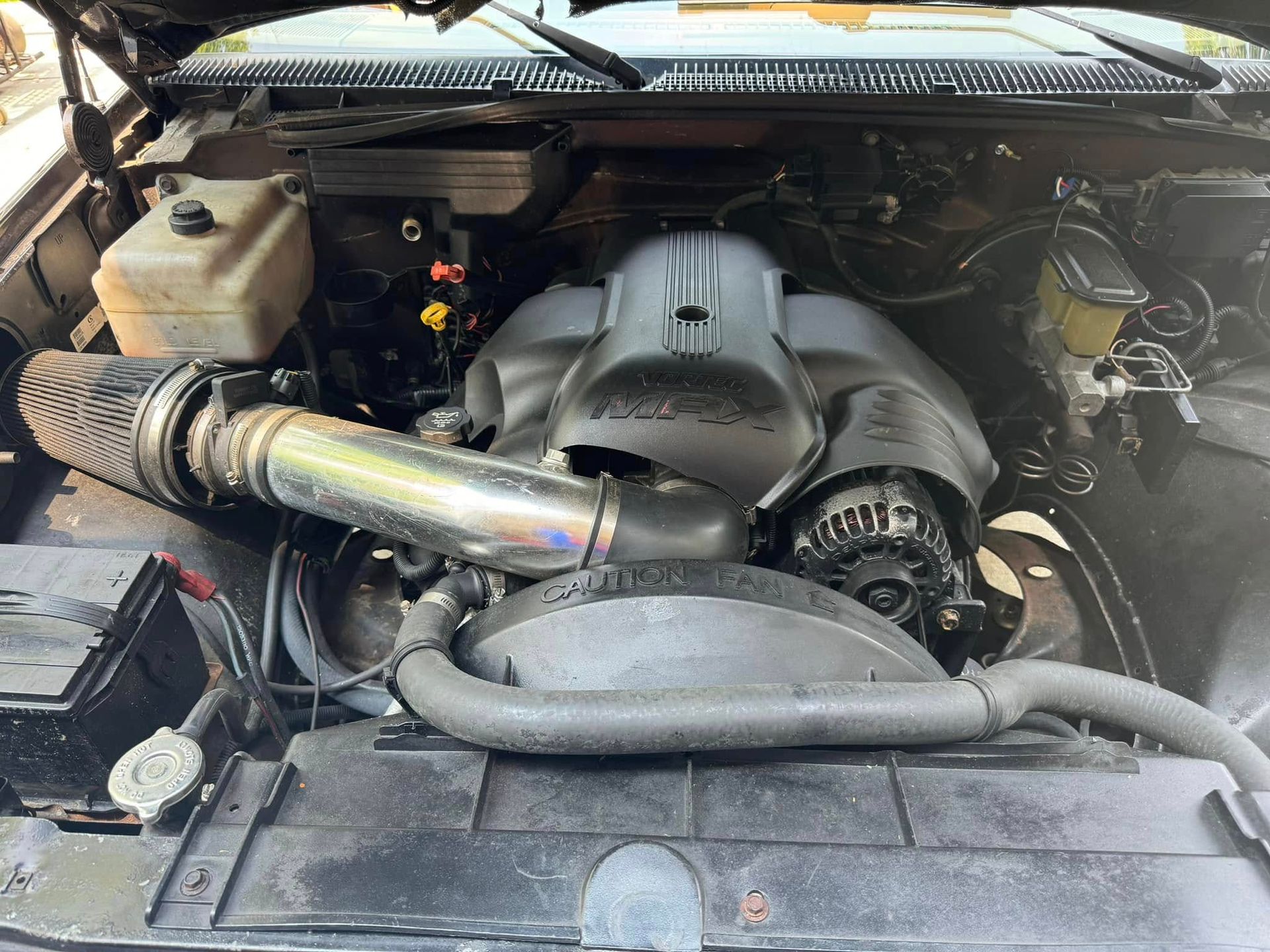 A close up of a car engine with the hood open.