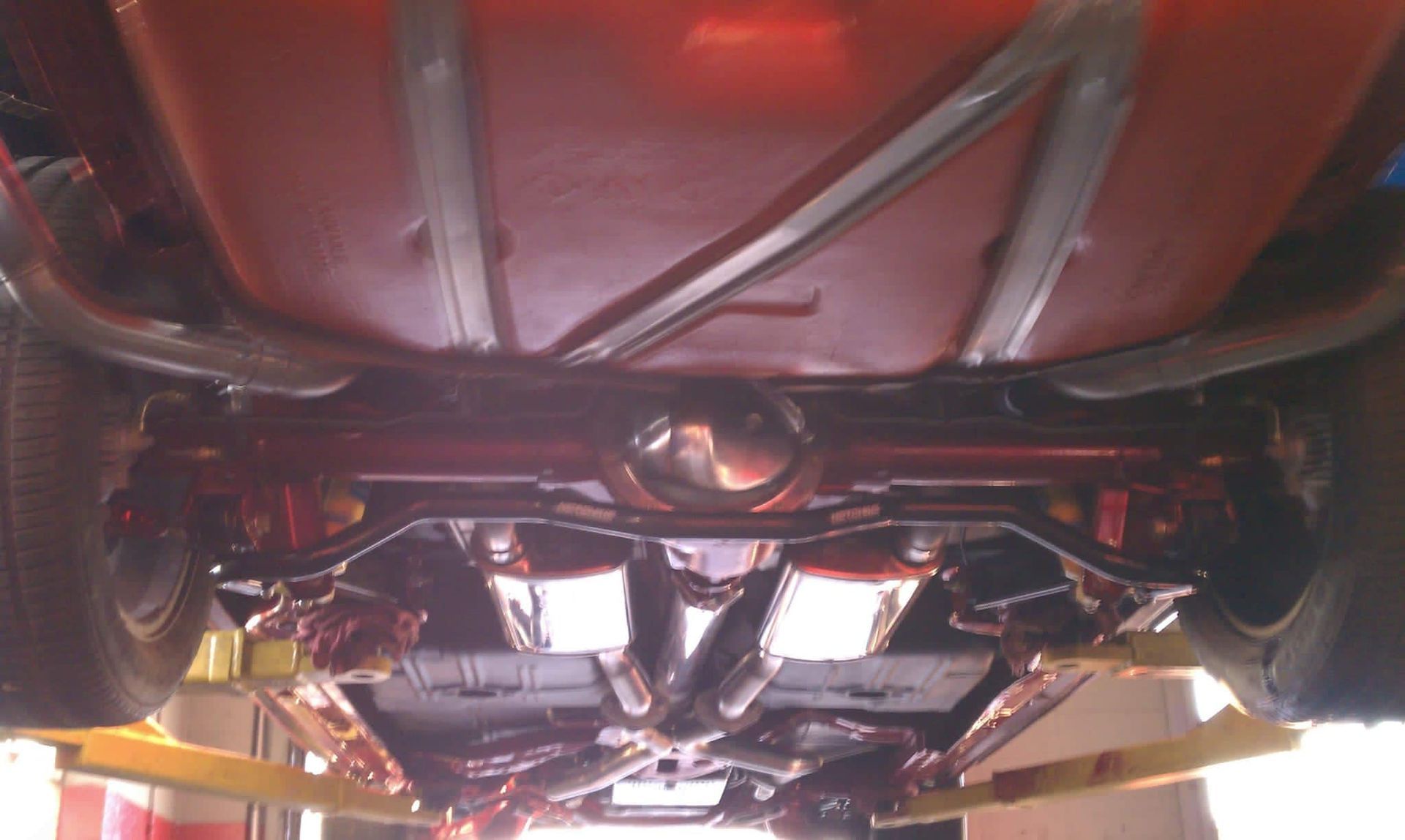 A red car is sitting on a lift in a garage