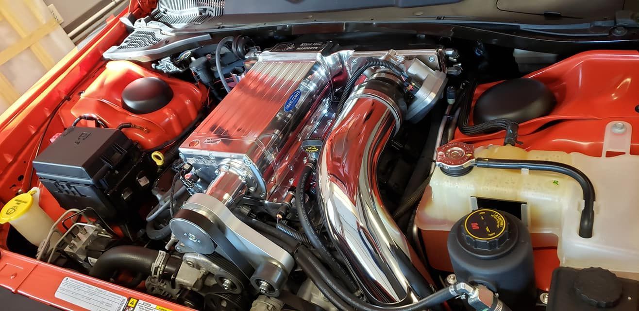 A close up of a red car engine with the hood open.