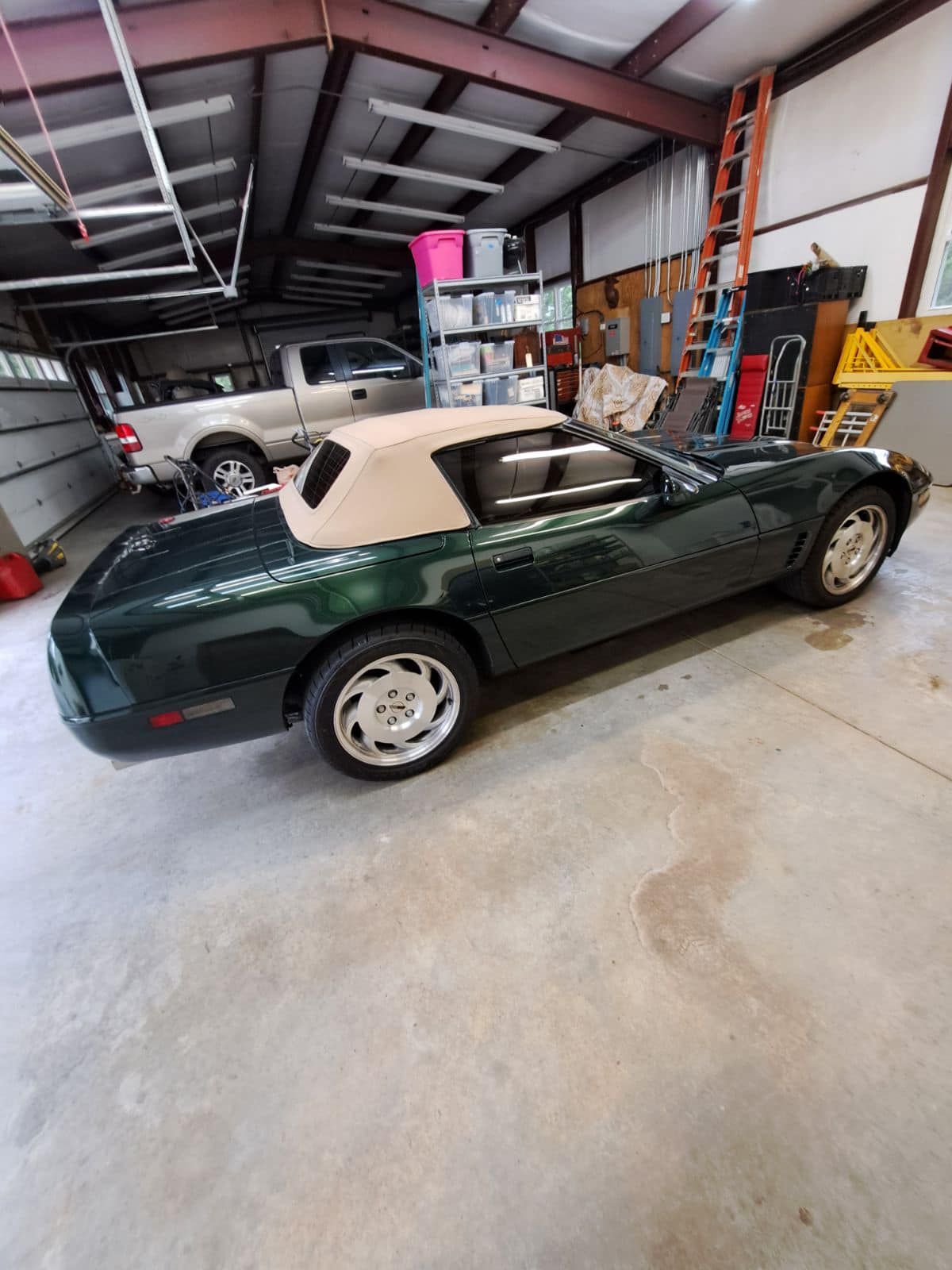 A green convertible car is parked in a garage.