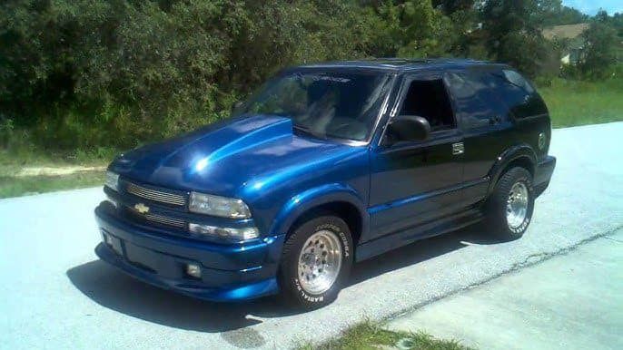 A blue chevrolet blazer is parked on the side of the road.