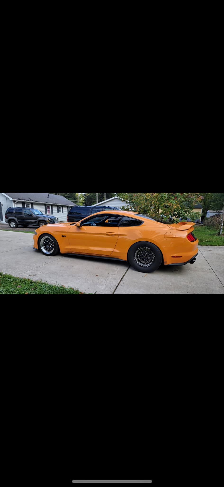 A yellow ford mustang is parked on the side of the road.