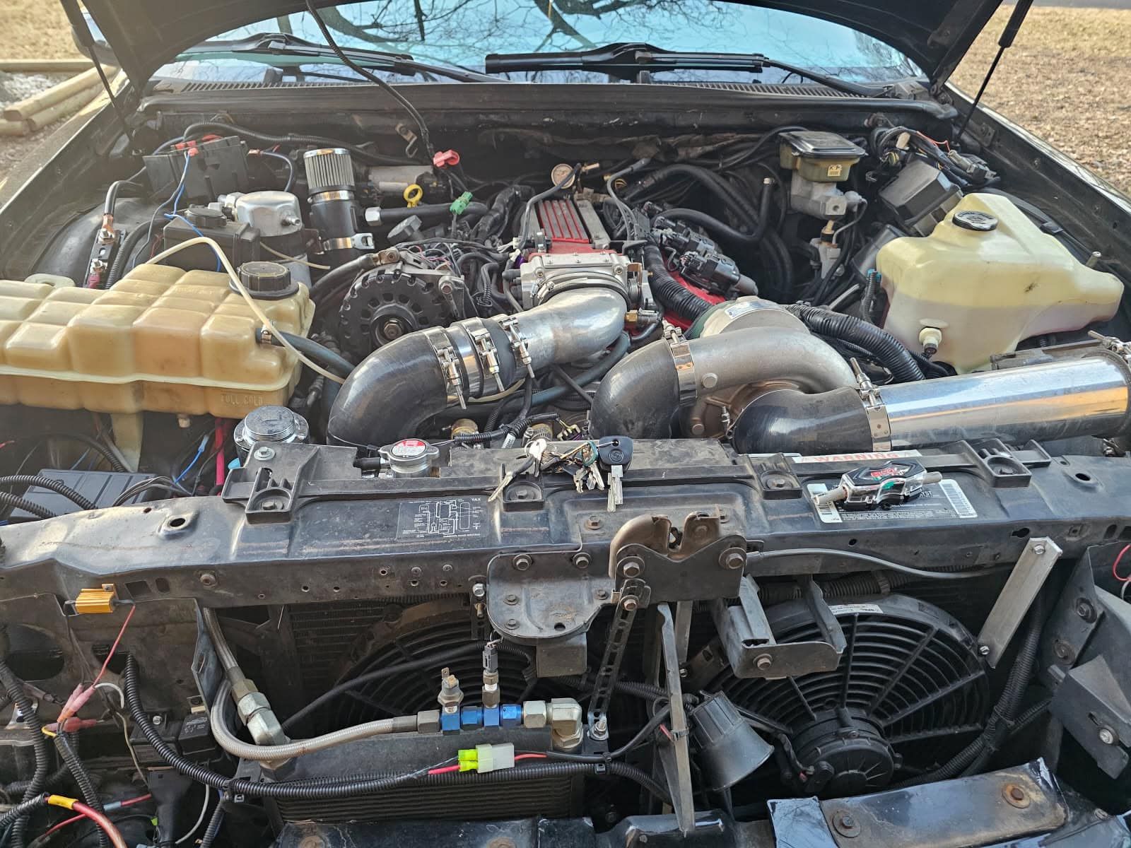 A black car with the hood up and the engine exposed.