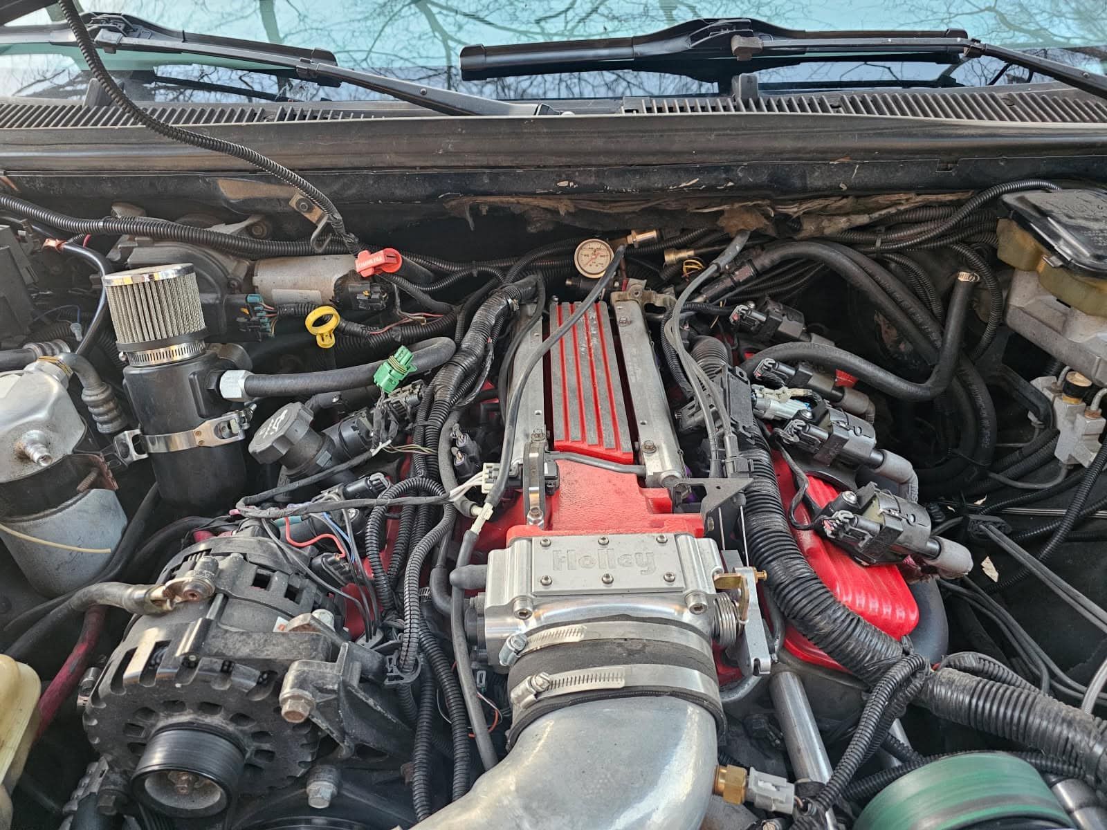 A close up of a car engine with a lot of wires coming out of it.