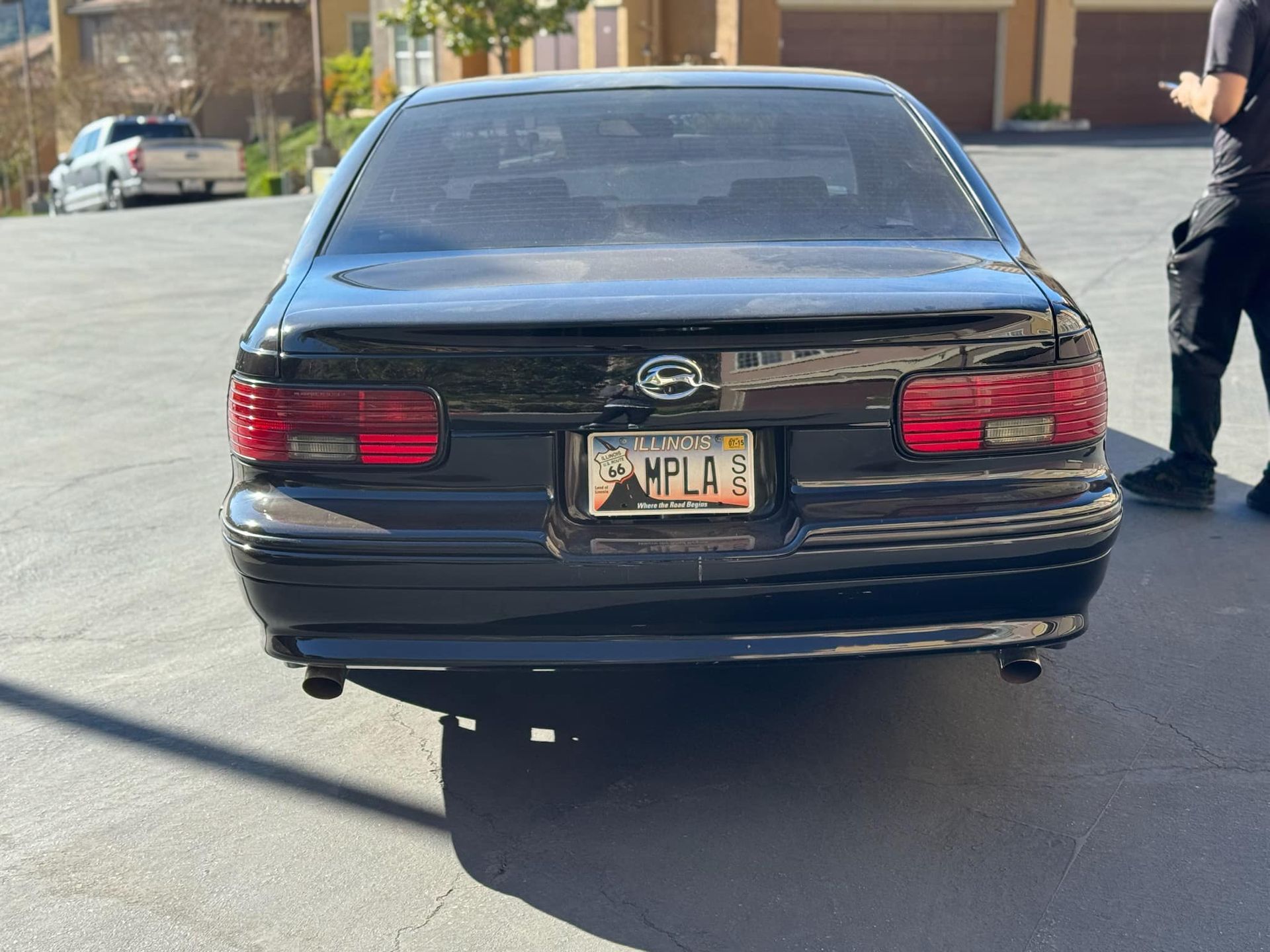 A black car with a new york license plate is parked on the side of the road.