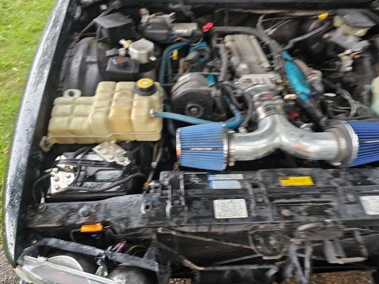 A close up of the engine of a car with a blue air filter.