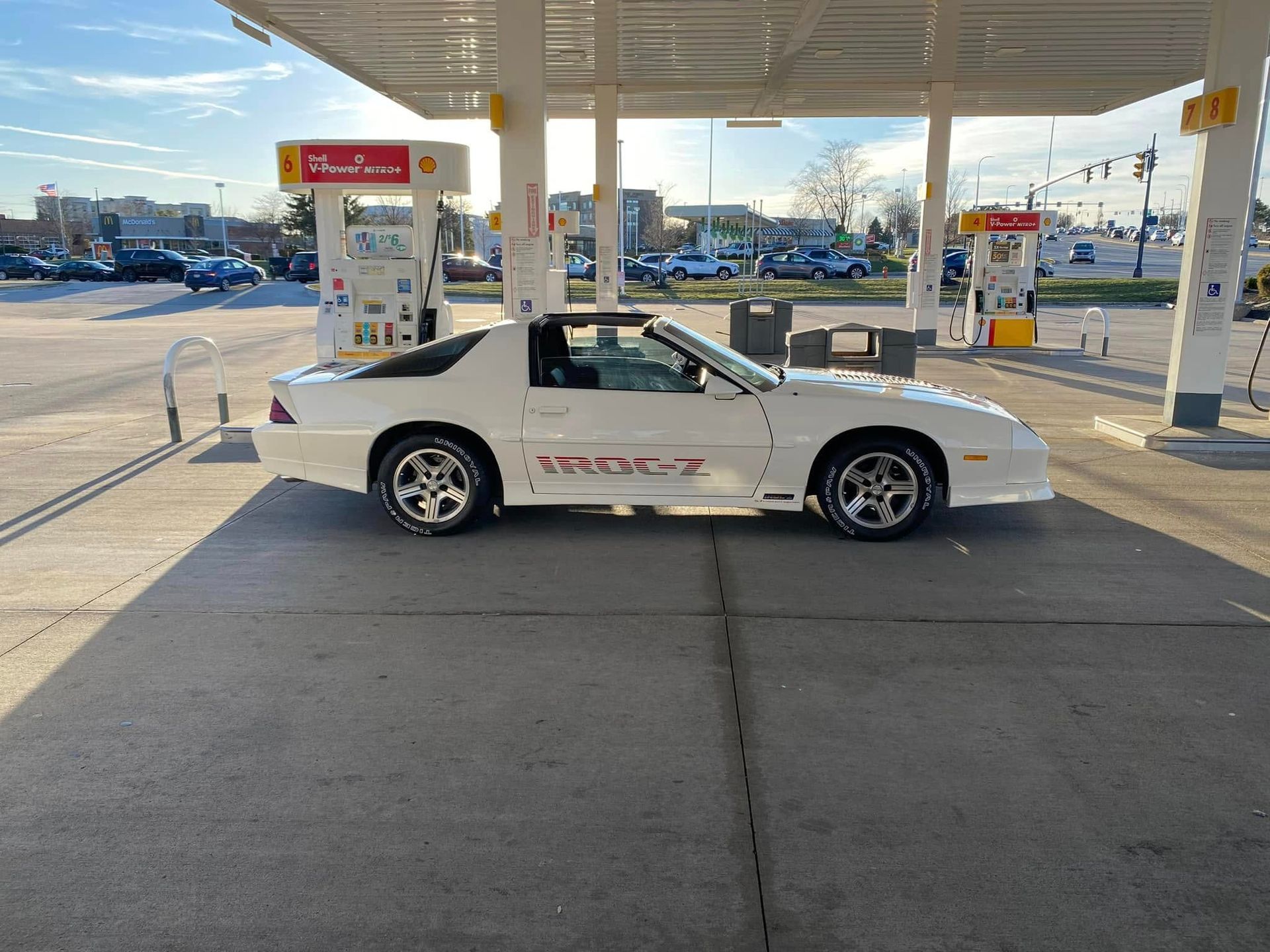A white car is parked in a gas station.