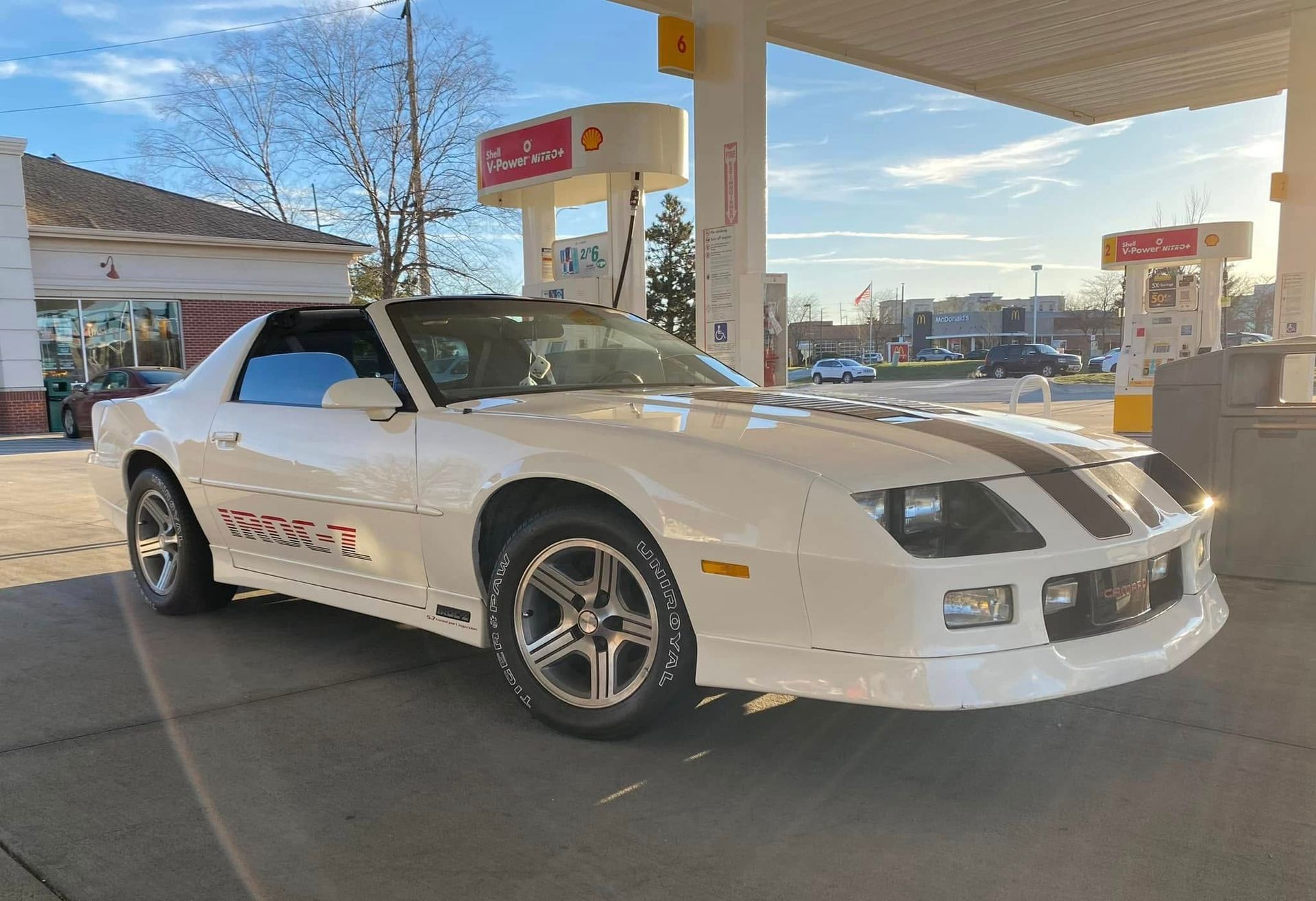 A white car is parked in front of a gas station.
