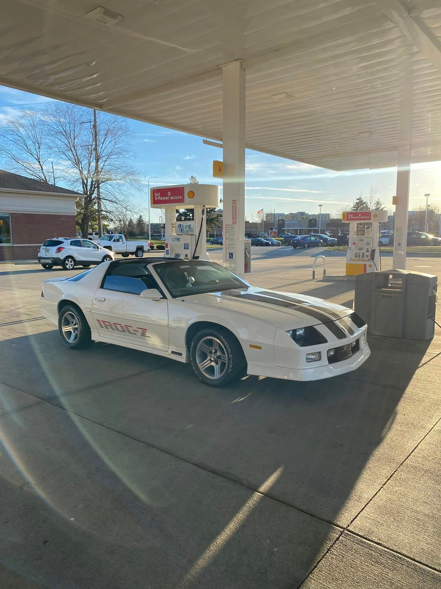 A white car is parked at a gas station.