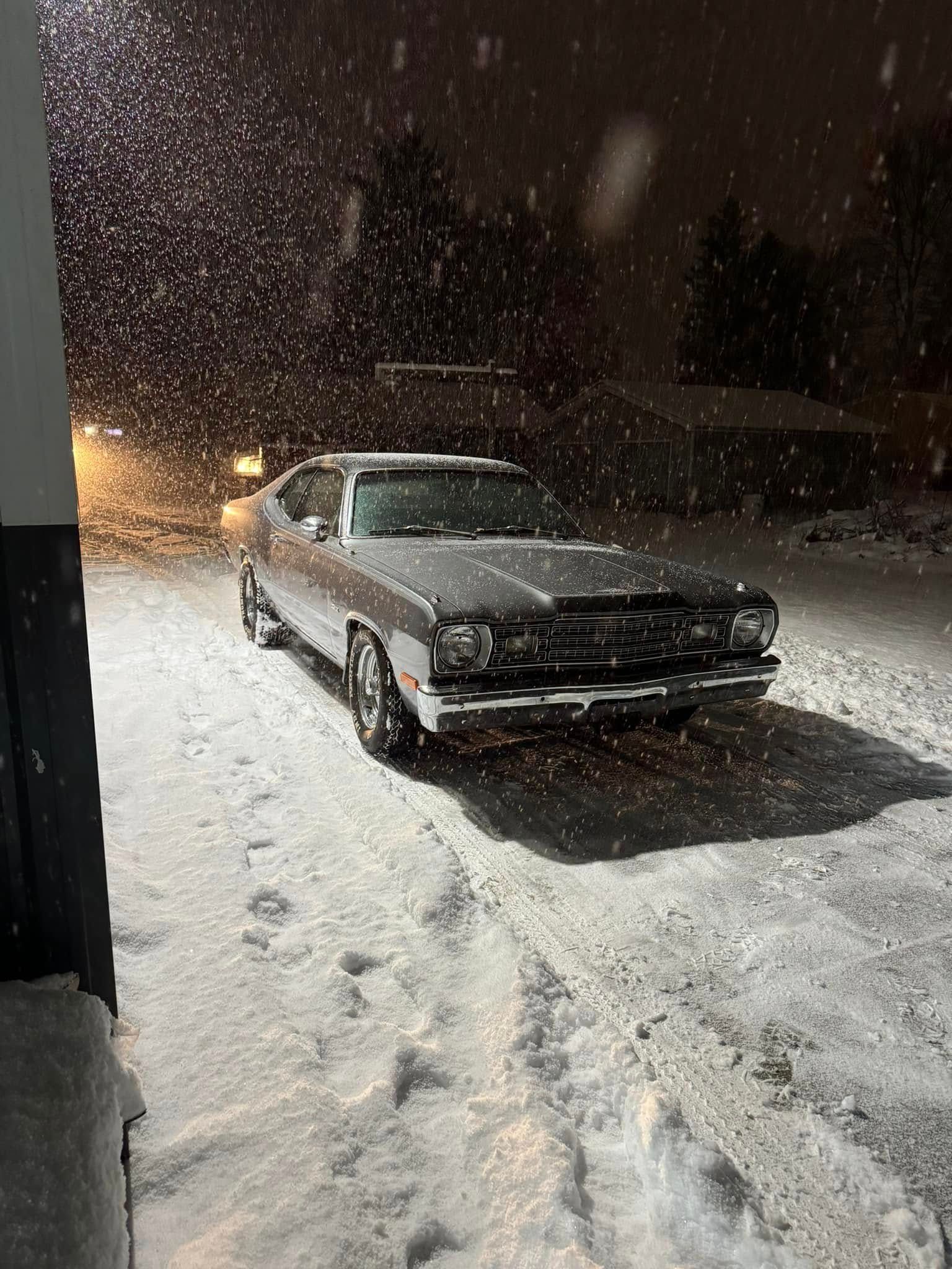 A car is parked in the snow at night.