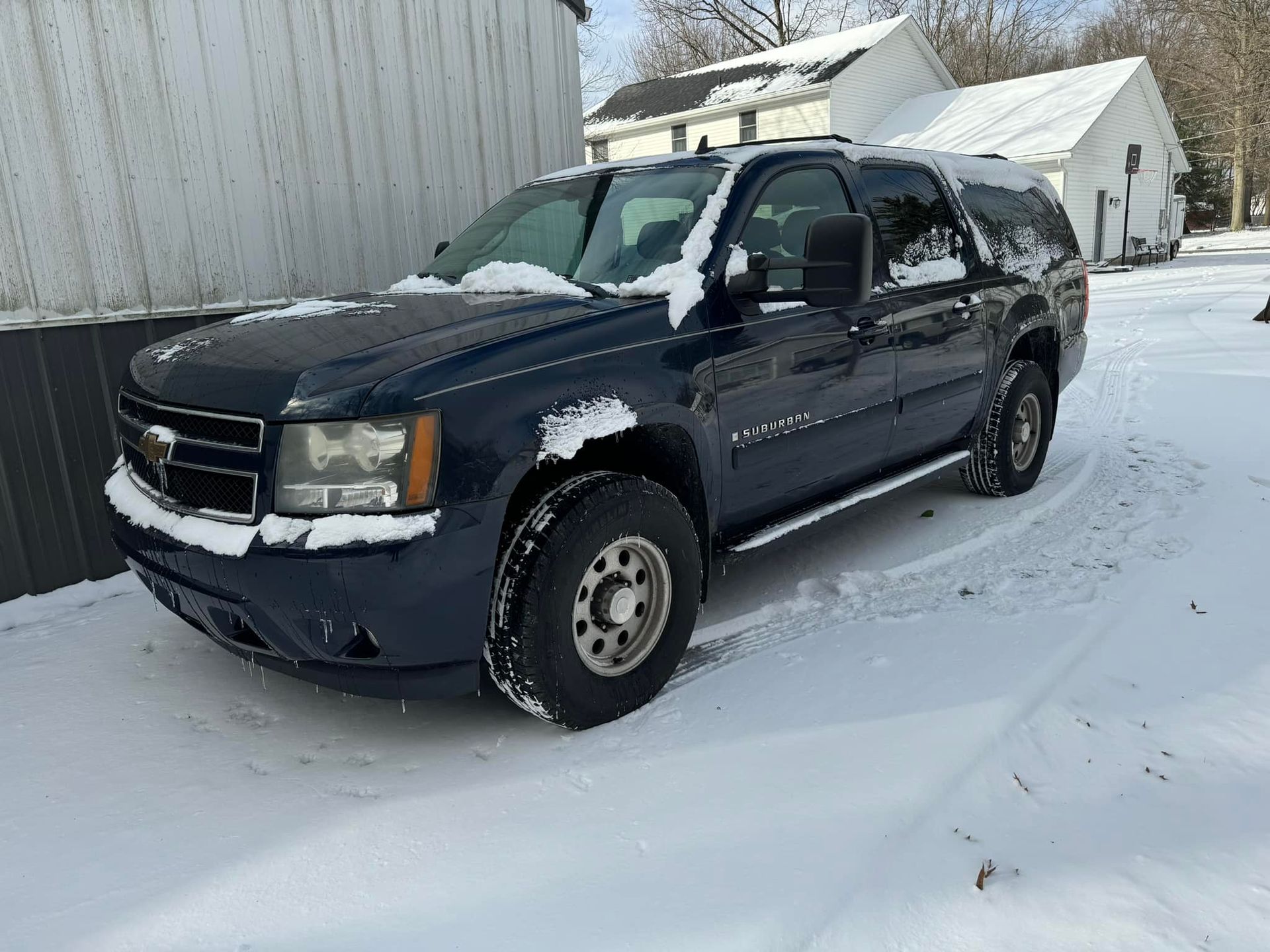A blue suv is parked in the snow in front of a building.
