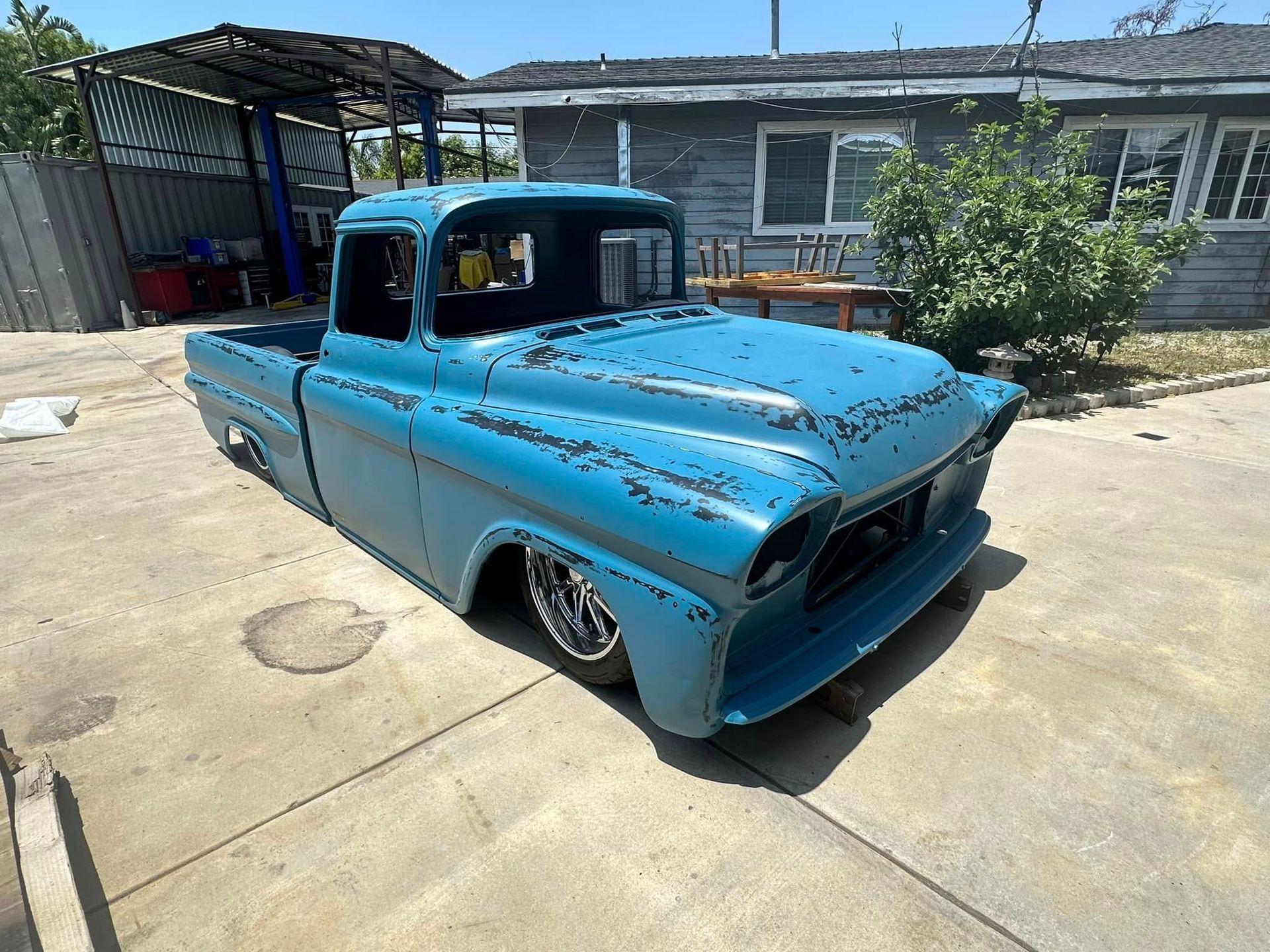 A blue truck is parked in a driveway in front of a house.