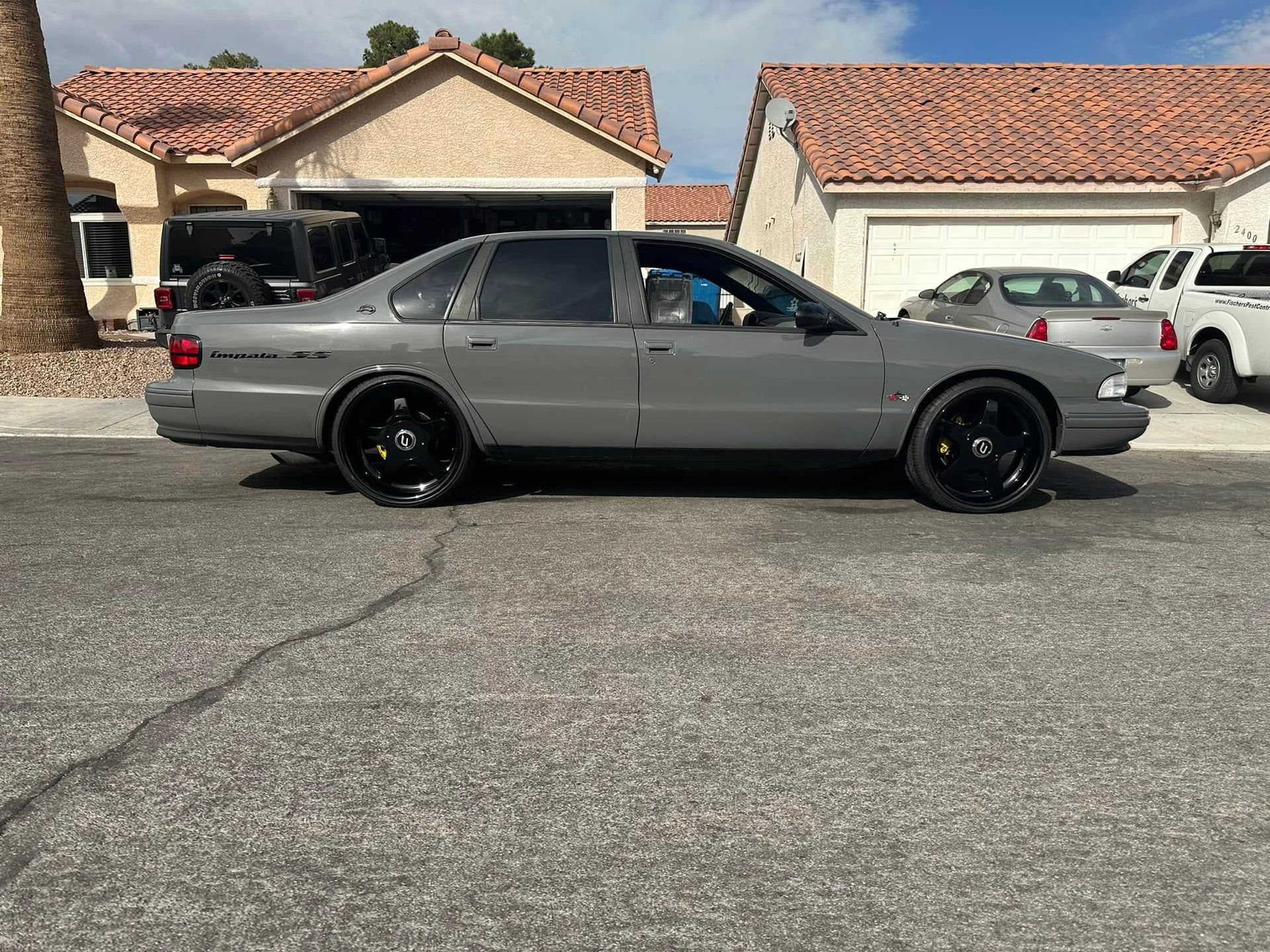 A gray car is parked on the side of the road in front of a house.