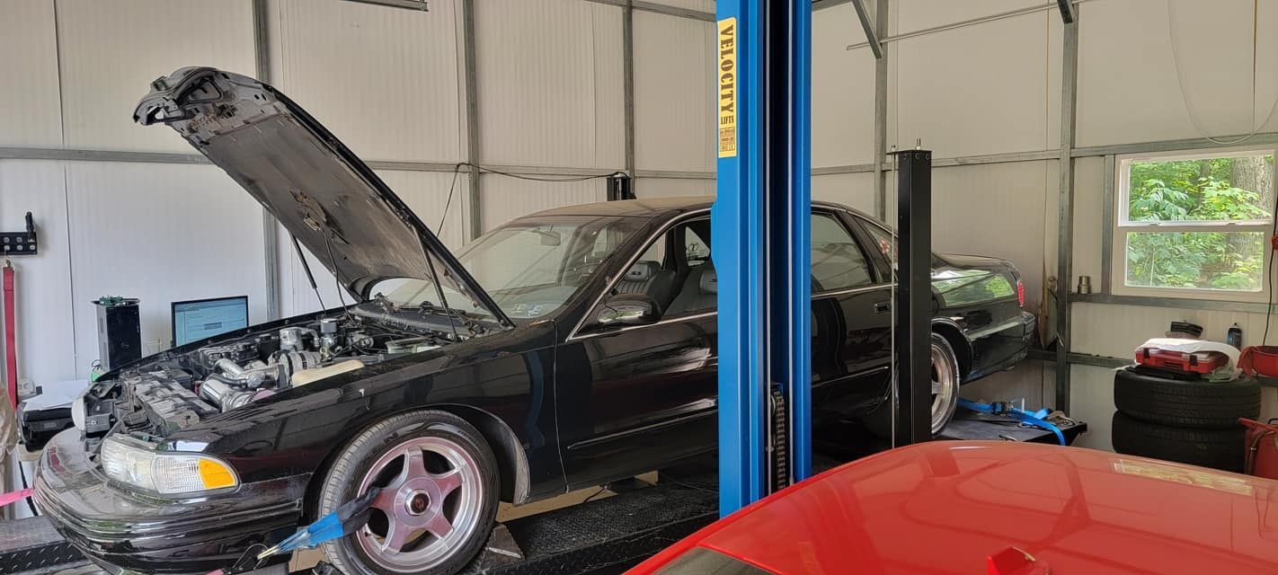 A black car is sitting on a lift in a garage.